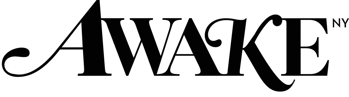 A black and white photo of a leafless tree in front of a cloudy sky.  Awake Clothing