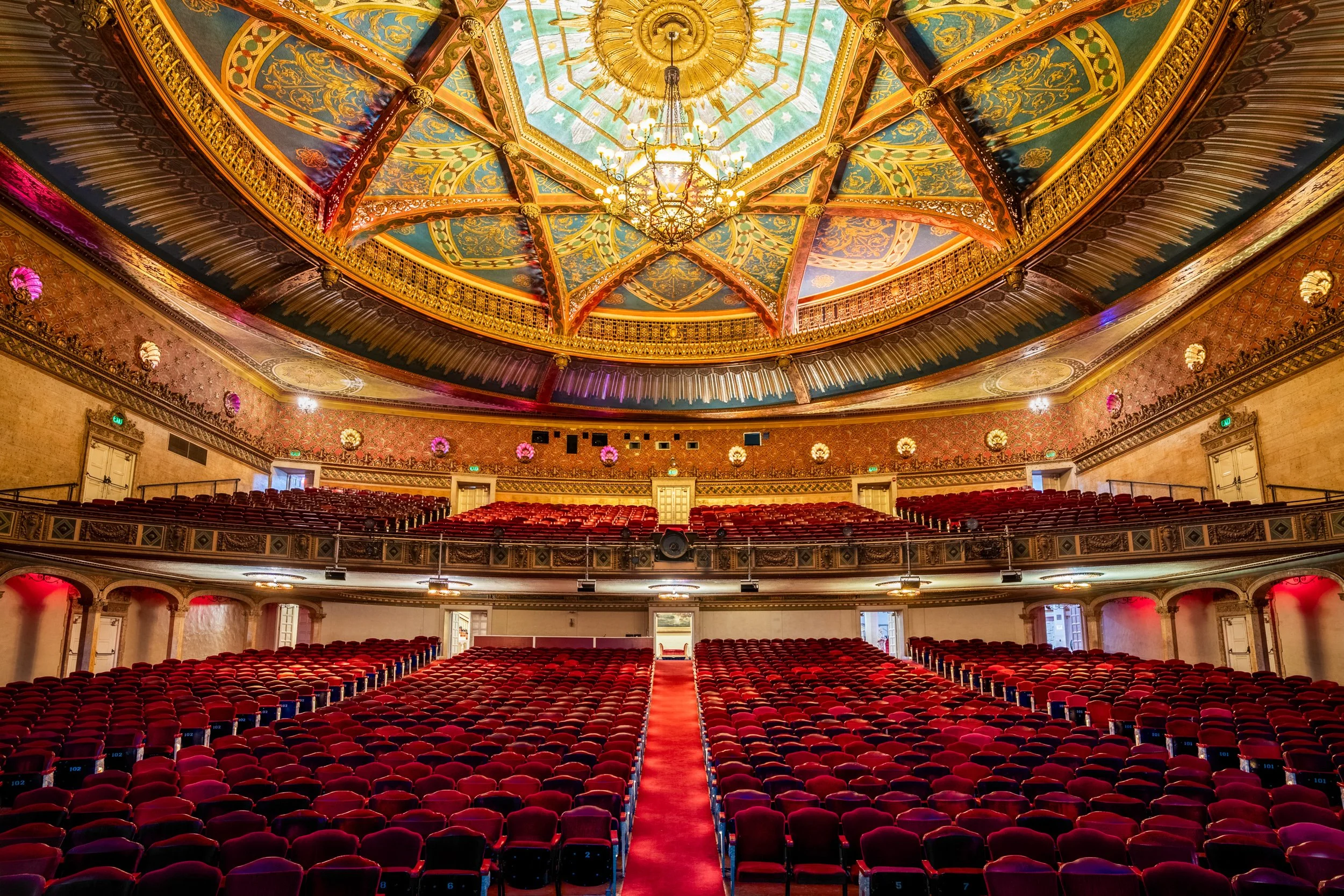 Historic Warnor theater interior from stage showing full red seating, ornate balconies, and painted ceiling dome — architectural photography by BK Captured