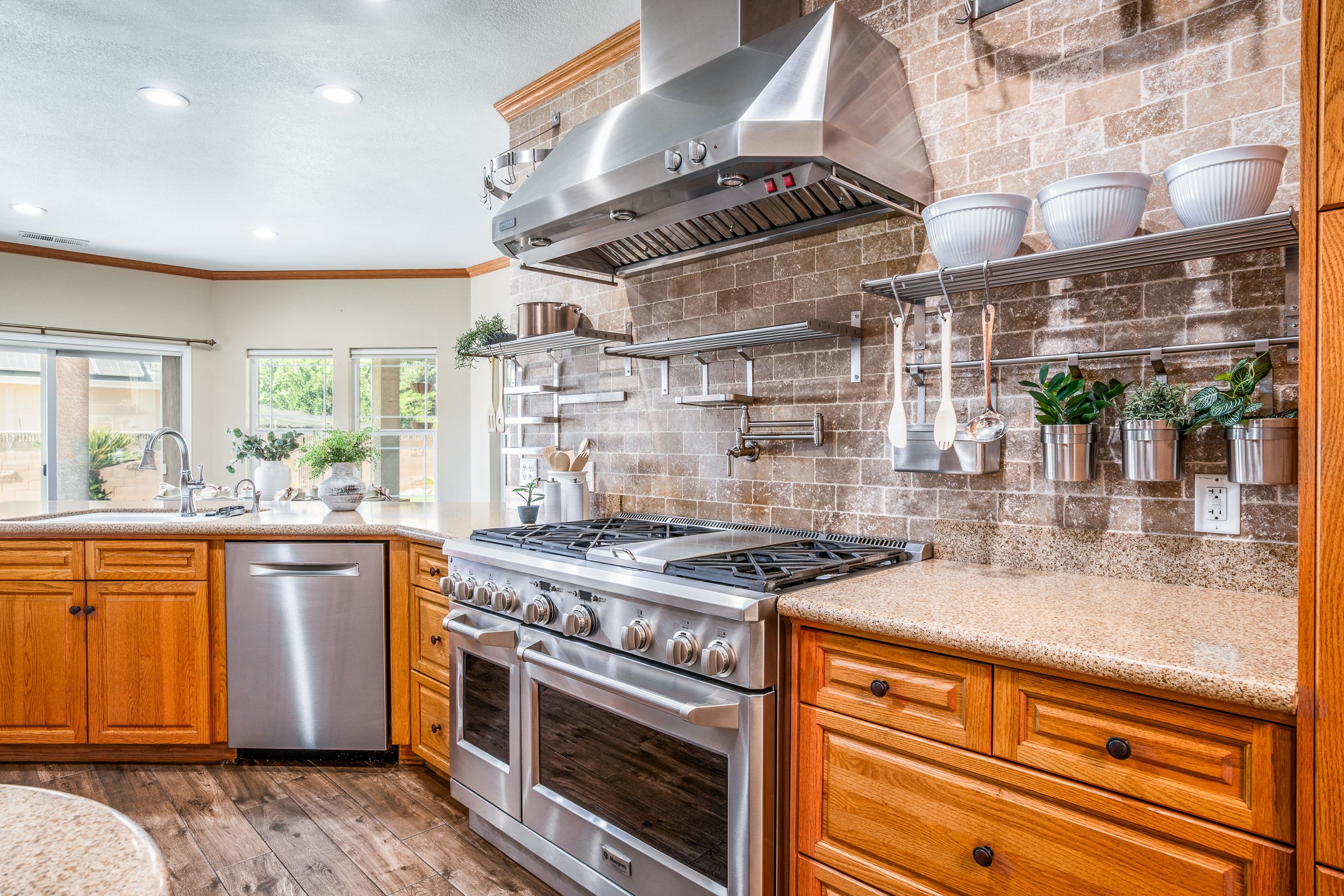 Chef's kitchen with oak cabinets, a stainless pro-range, vent hood, and stone-tile backsplash