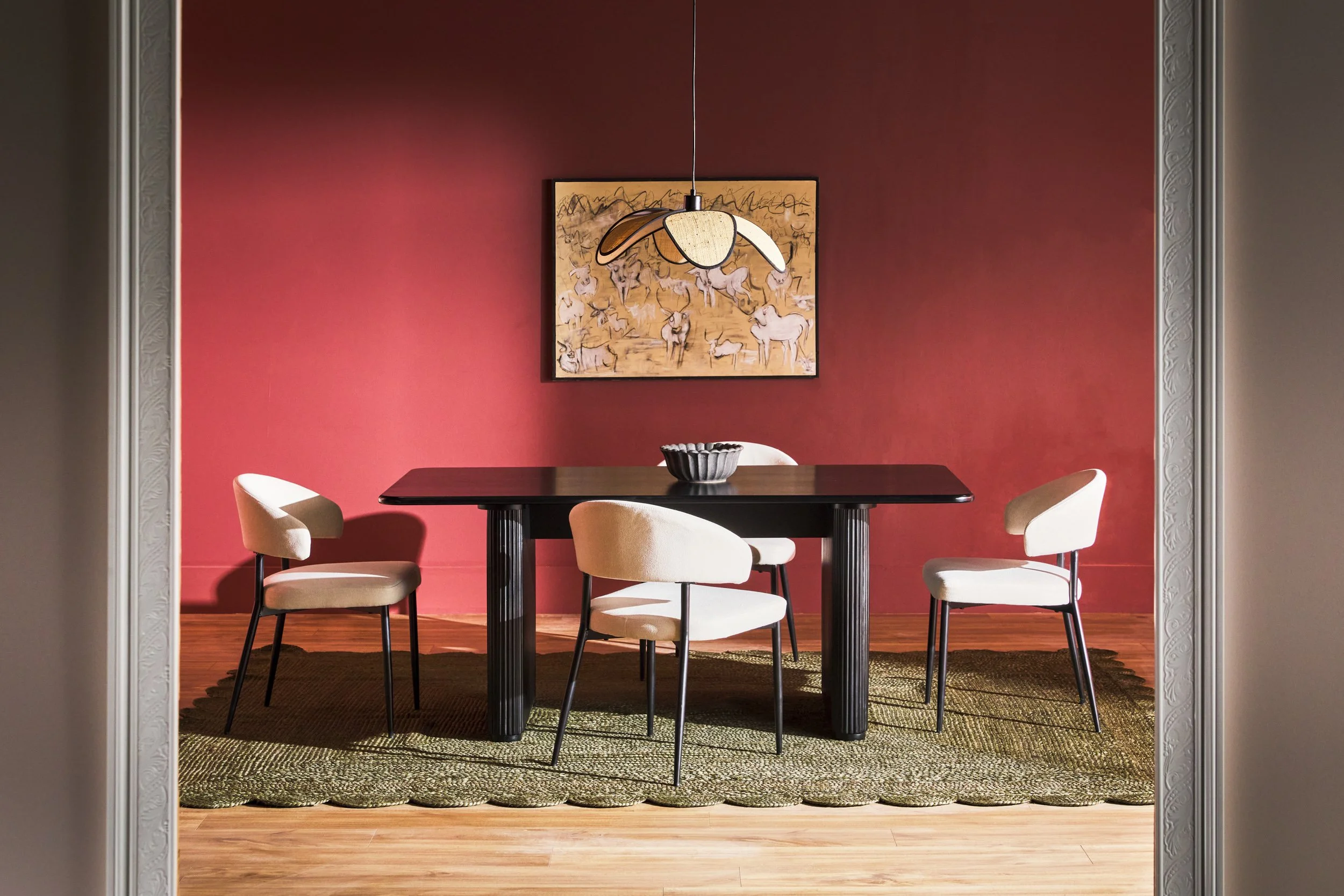 Walker Edison black dining table and white chairs against a deep red wall with pendant lighting and framed gallery art — editorial furniture photography by BK Captured