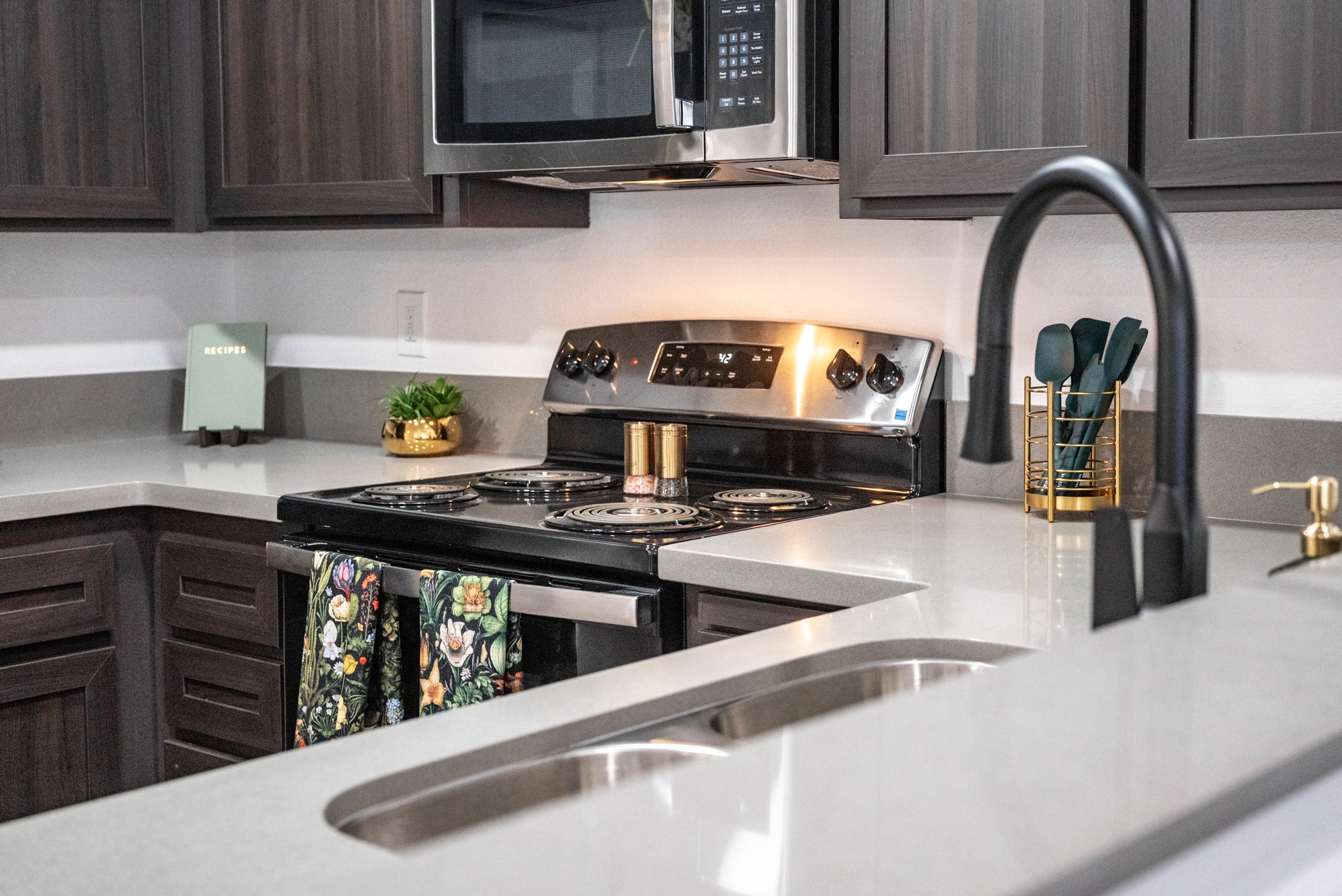 Apartment kitchen with dark wood cabinets, stainless range, and quartz countertops