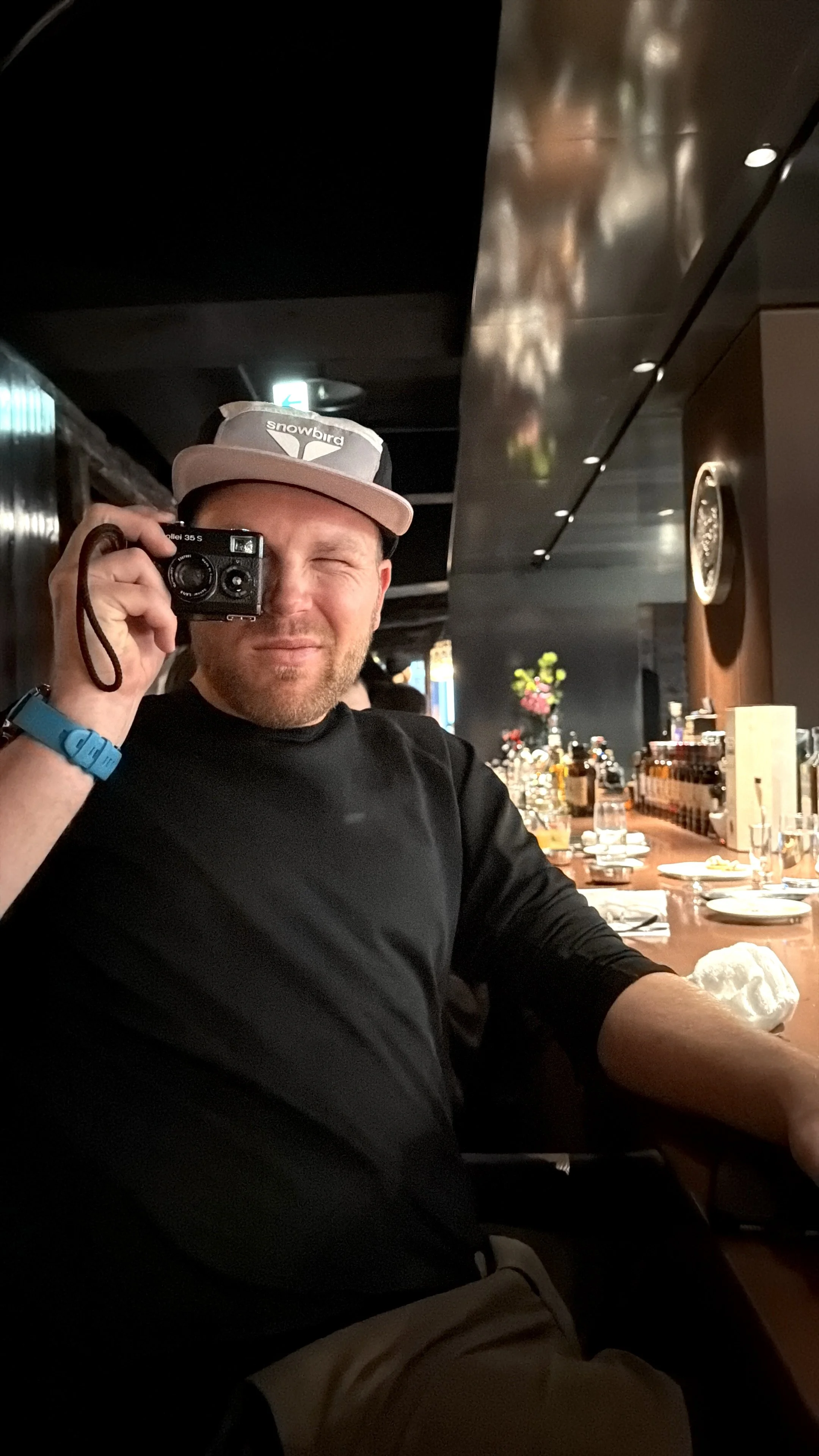 Berin Klawiter holding a Rollei 35S film camera at a restaurant bar — commercial photographer behind BK Captured
