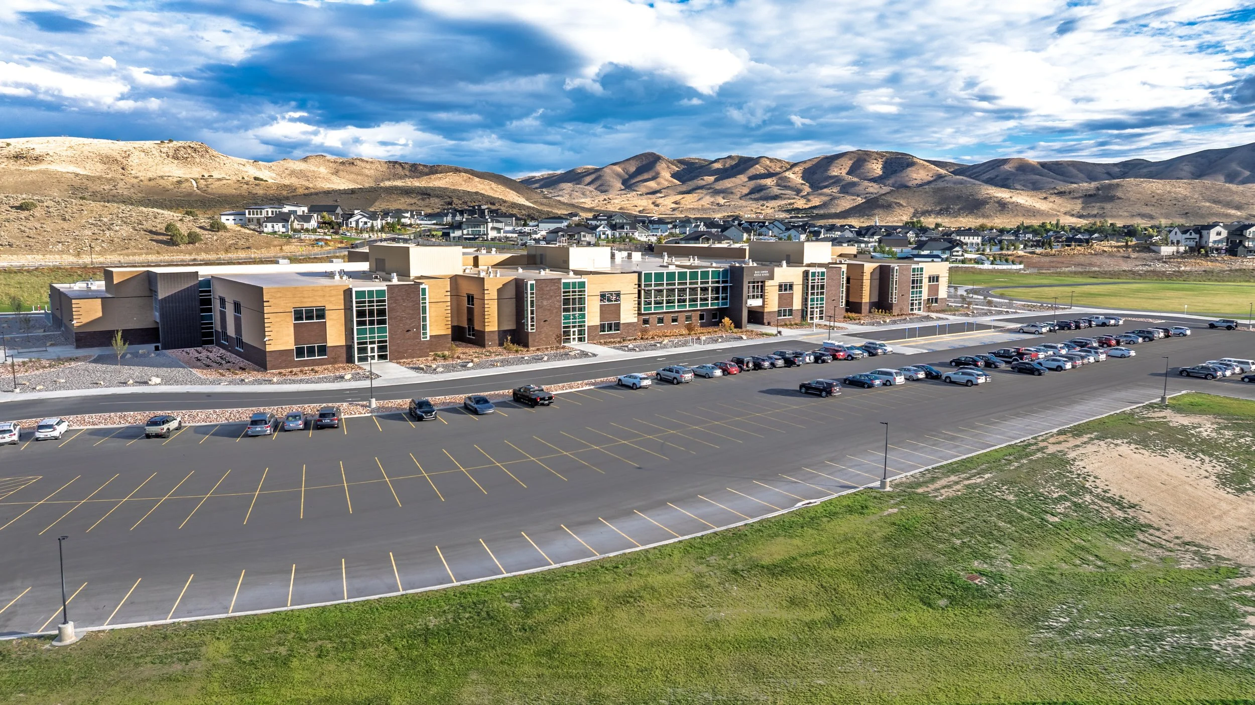 Aerial view of school campus with large parking lot and mountains behind — educational facility photography by BK Captured