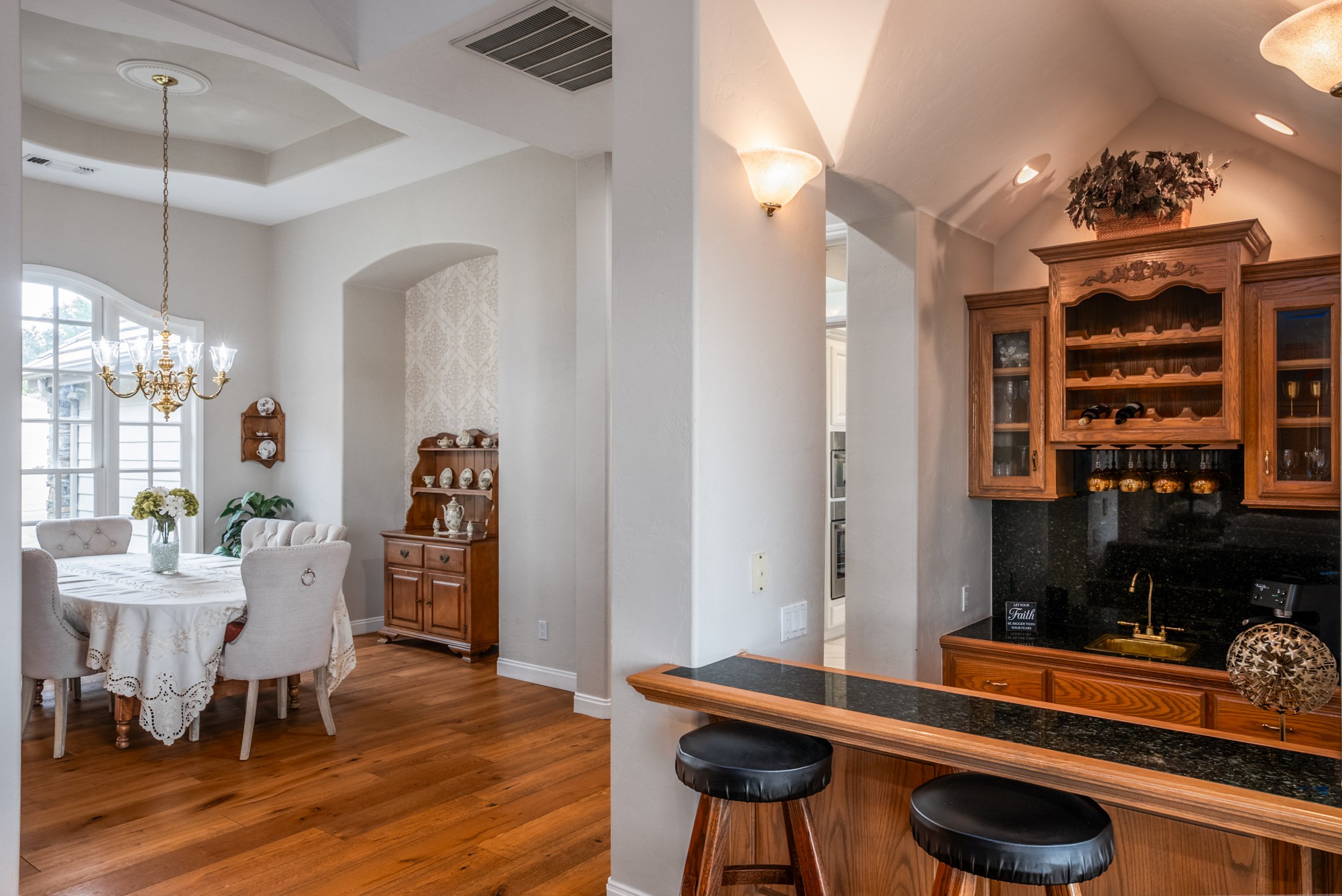 Open dining area and oak wet bar with granite counters and warm hardwood floors