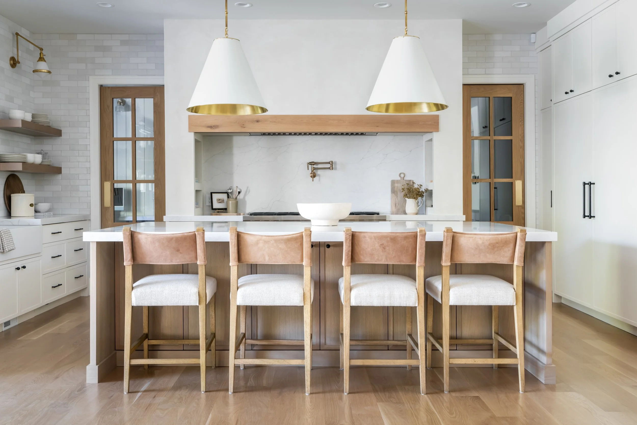 Bright custom kitchen with white cabinetry, island bar seating, and pendant lighting — interior architectural photography by BK Captured