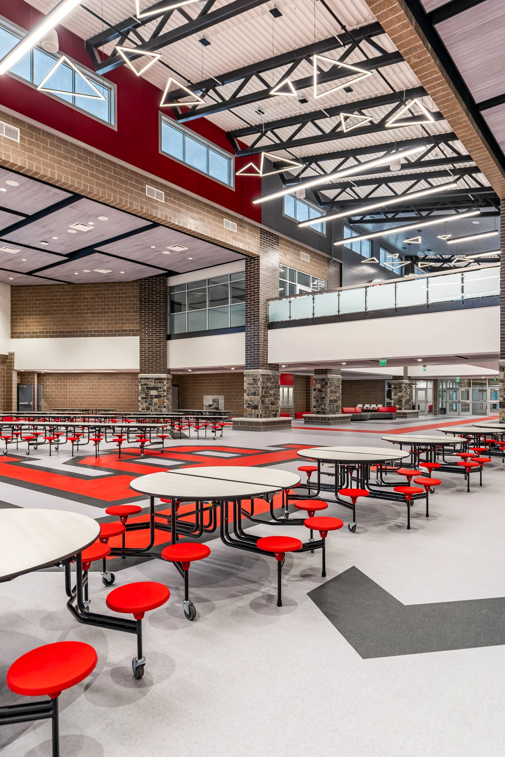 Modern school cafeteria with red stools and open ceiling structure — educational facility architectural photography by BK Captured