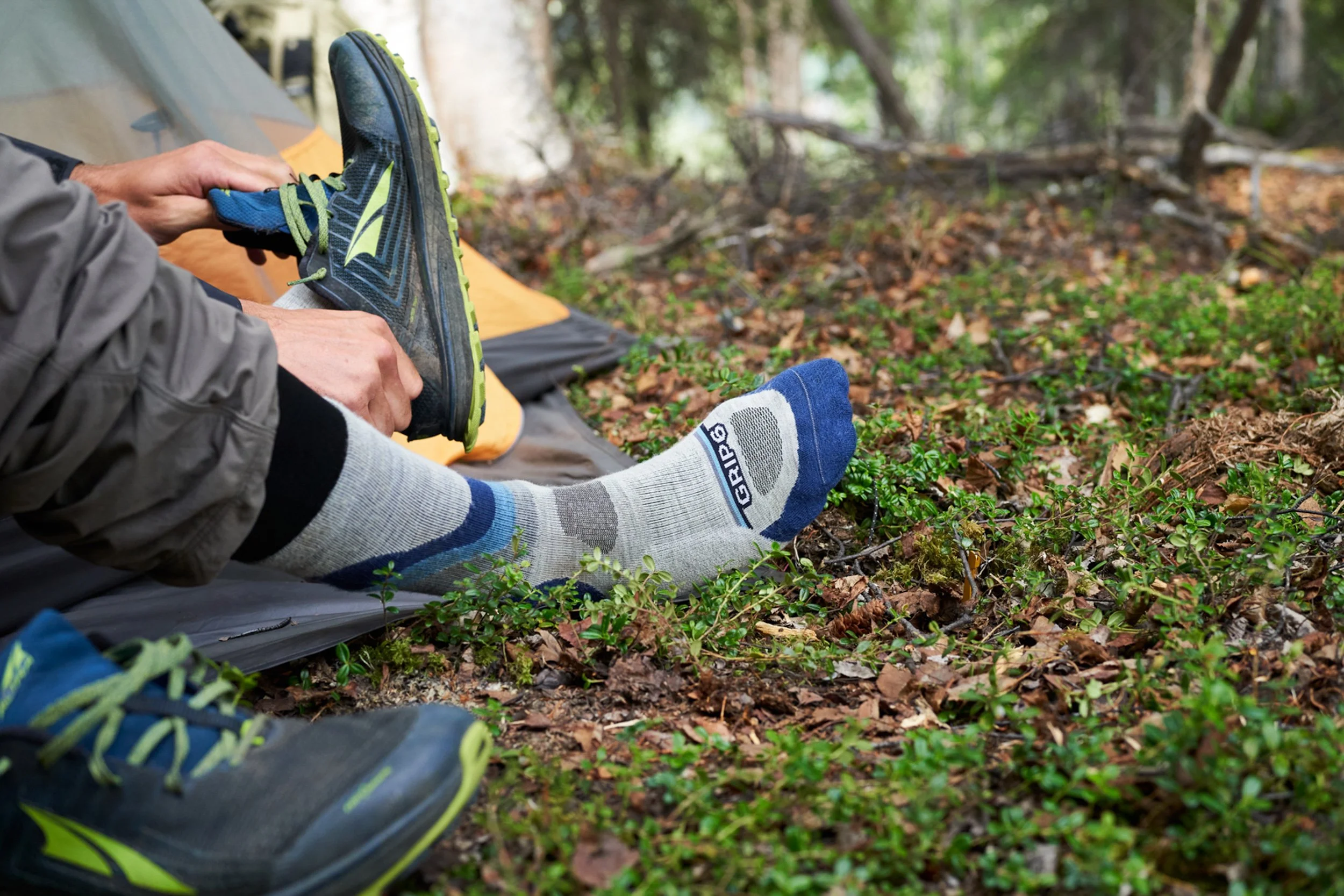 Person putting on sock at forested campsite Grip6 product lifestyle product photography