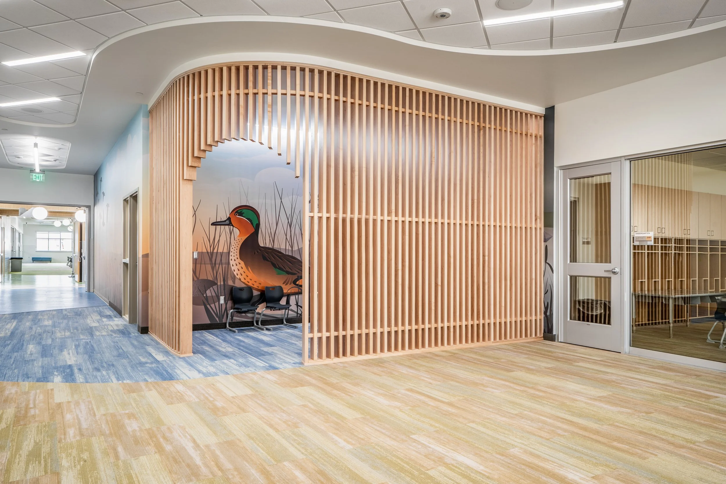 Curved slatted wood accent wall in modern interior corridor with warm ambient lighting — architectural interior photography by BK Captured