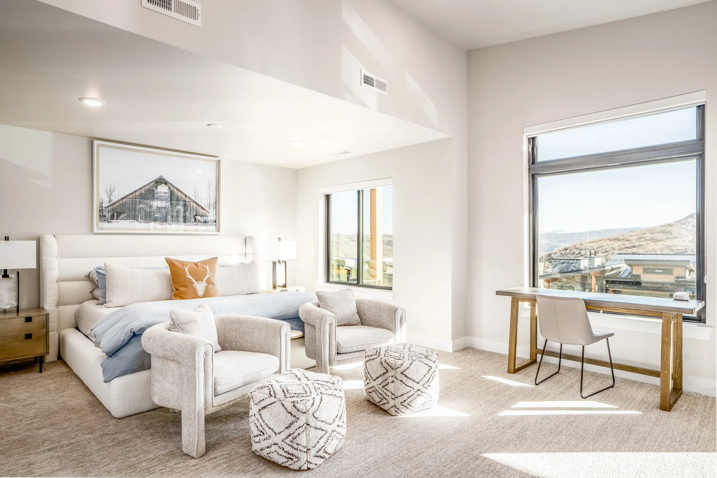 Bright custom home bedroom with white sofa and floor-to-ceiling windows overlooking mountain views — interior architectural photography by BK Captured