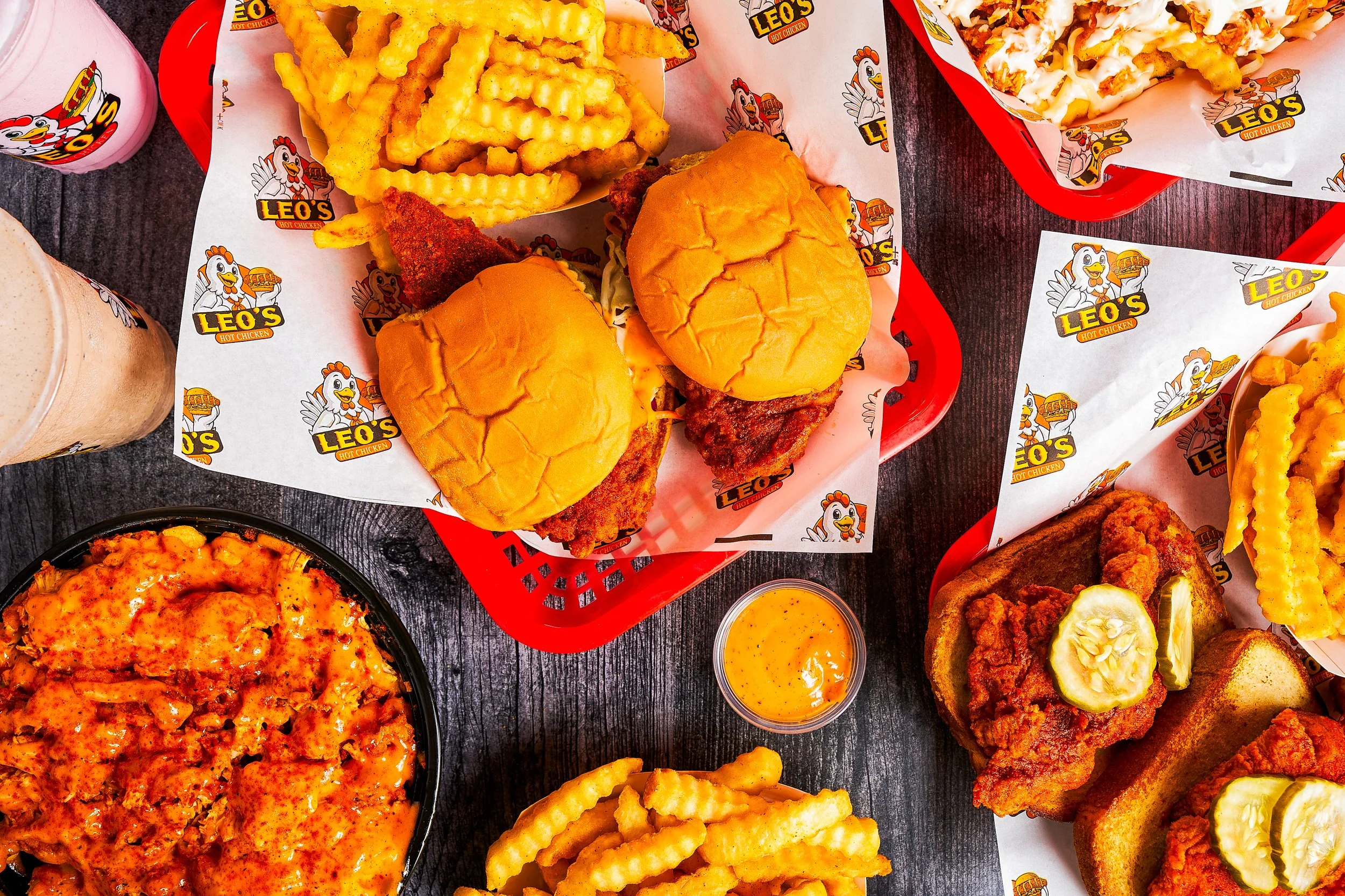 Overhead flatlay of Leo's Hot Chicken Fresno menu including hot chicken sandwiches, crinkle fries, tenders, and mac and cheese on wood surface — restaurant photography by BK Captured