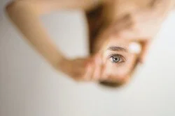 A person's hand holding a mirror reflecting their eye and face
