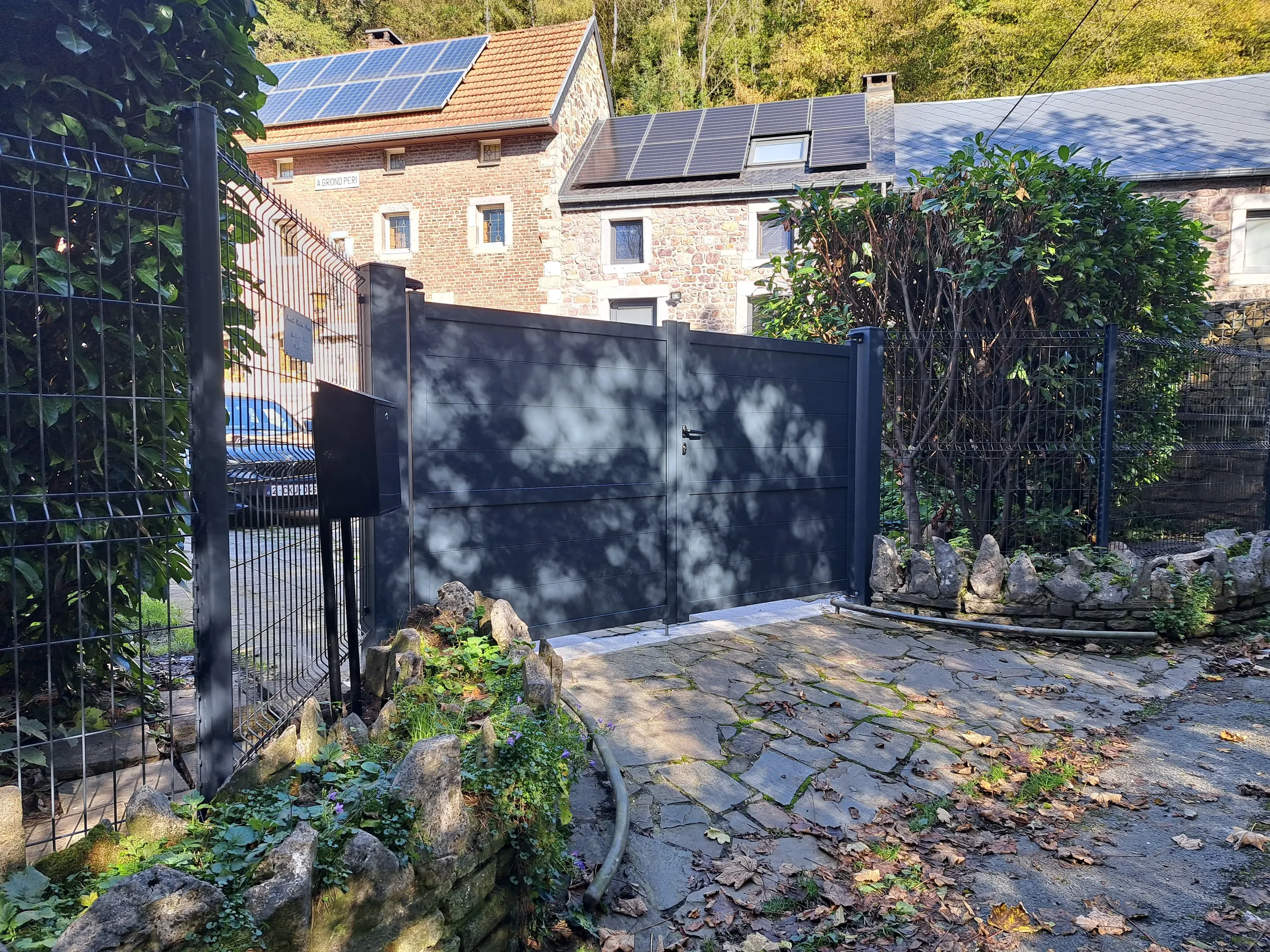 Pose de portail battant plein gris anthracite sur mur en pierre à Marchin - Clair et Vert