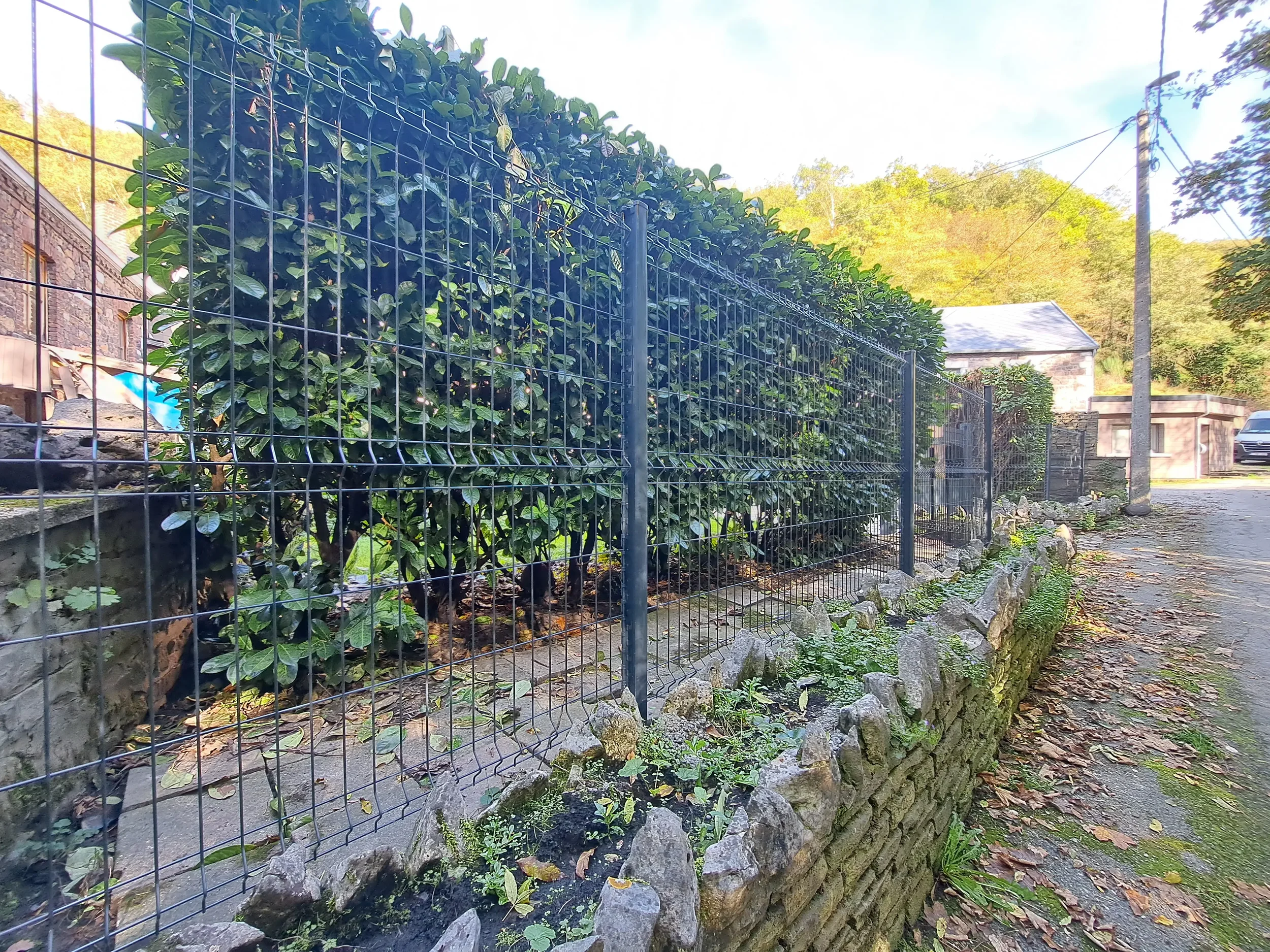 Clôture rigide sur muret en pierre avec haie de lauriers à Huy - Marchin