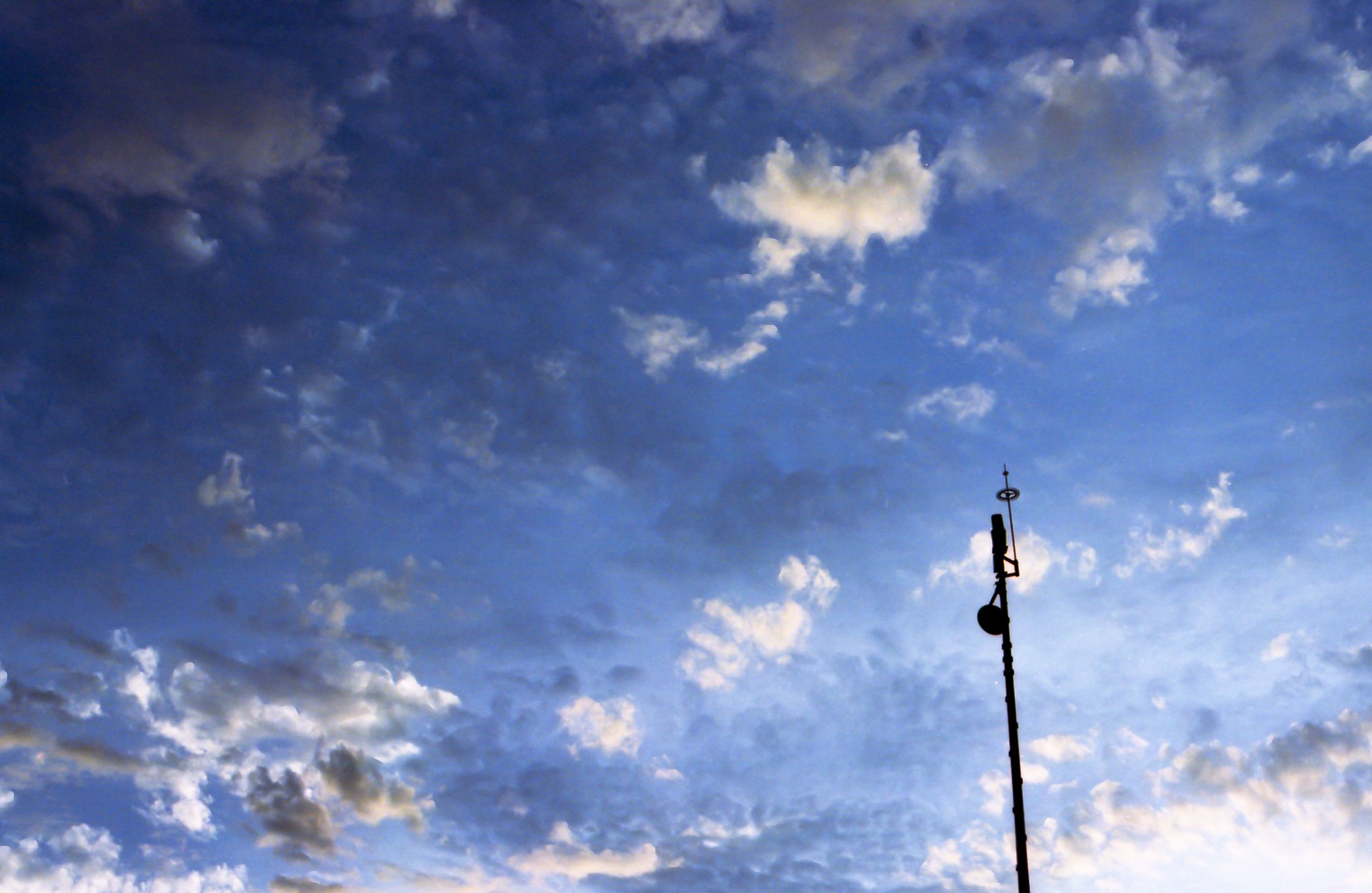 Cielo despejado con nubes dispersas y una antena en primer plano.