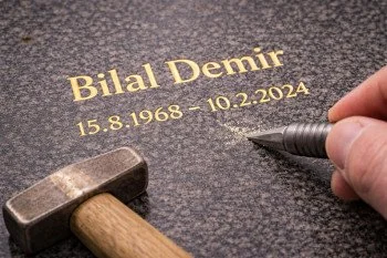 Grabstein mit Inschrift in Gold.