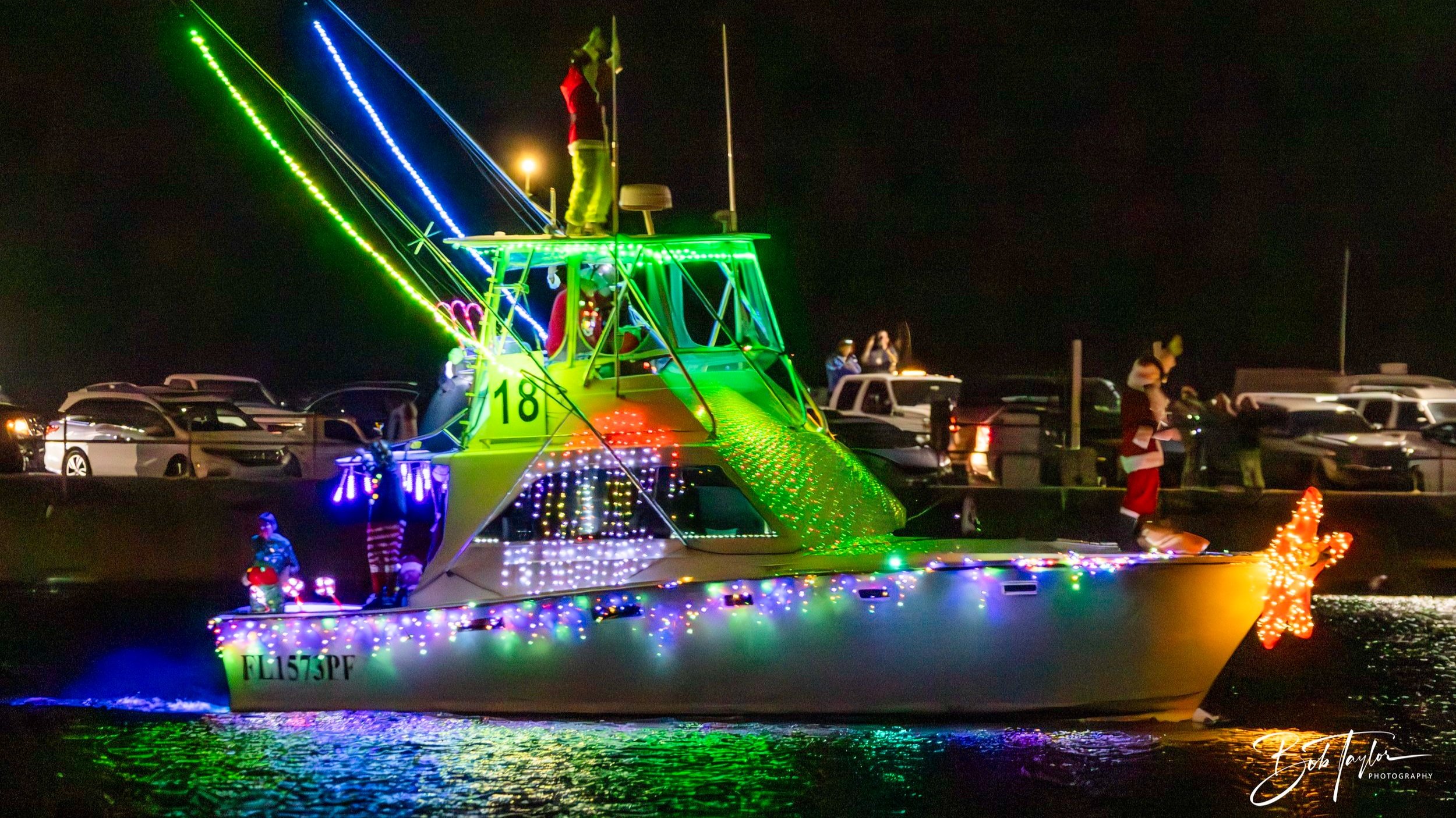 Photo of a sport fishing boat at night decorated with holiday lights in a boat parade