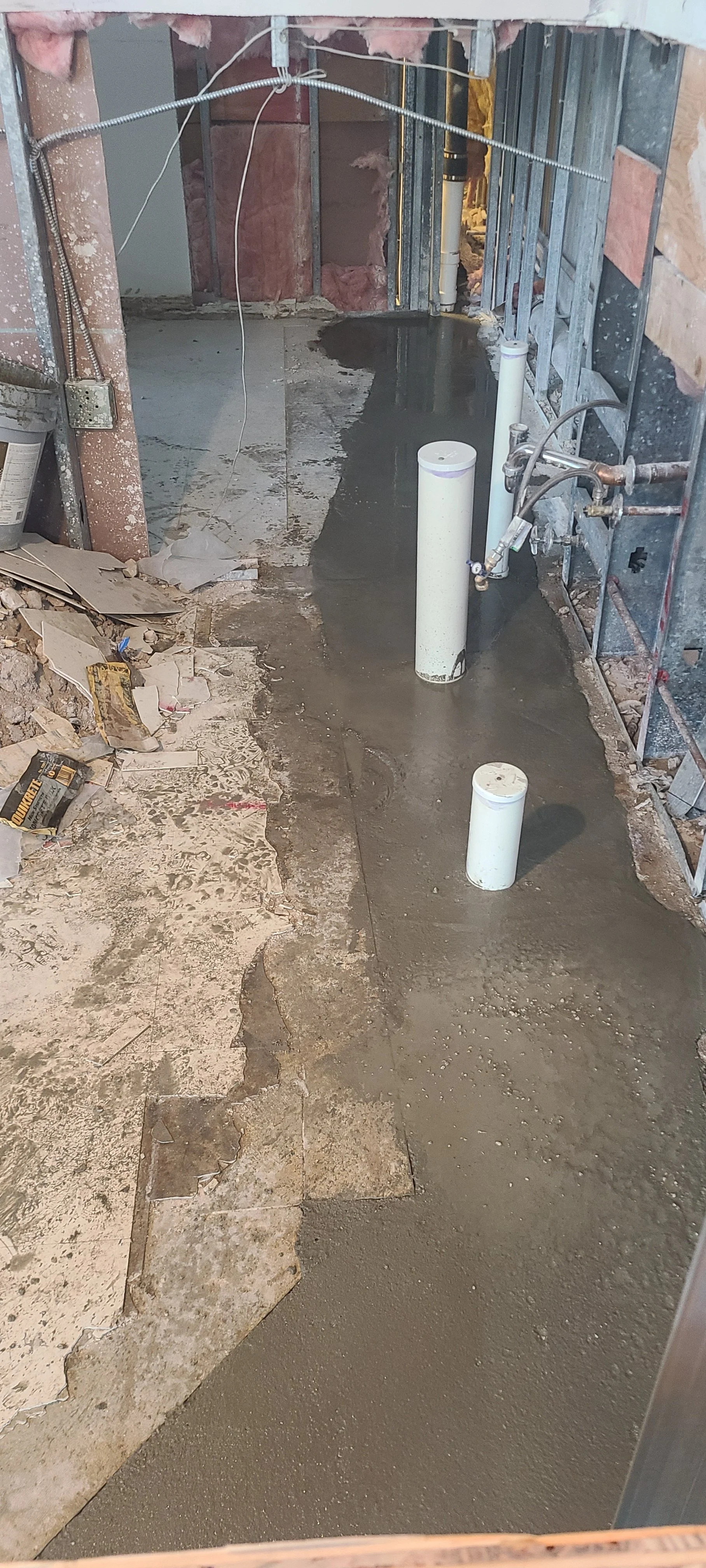 Bathroom renovation with fresh concrete subfloor, new plumbing drains.