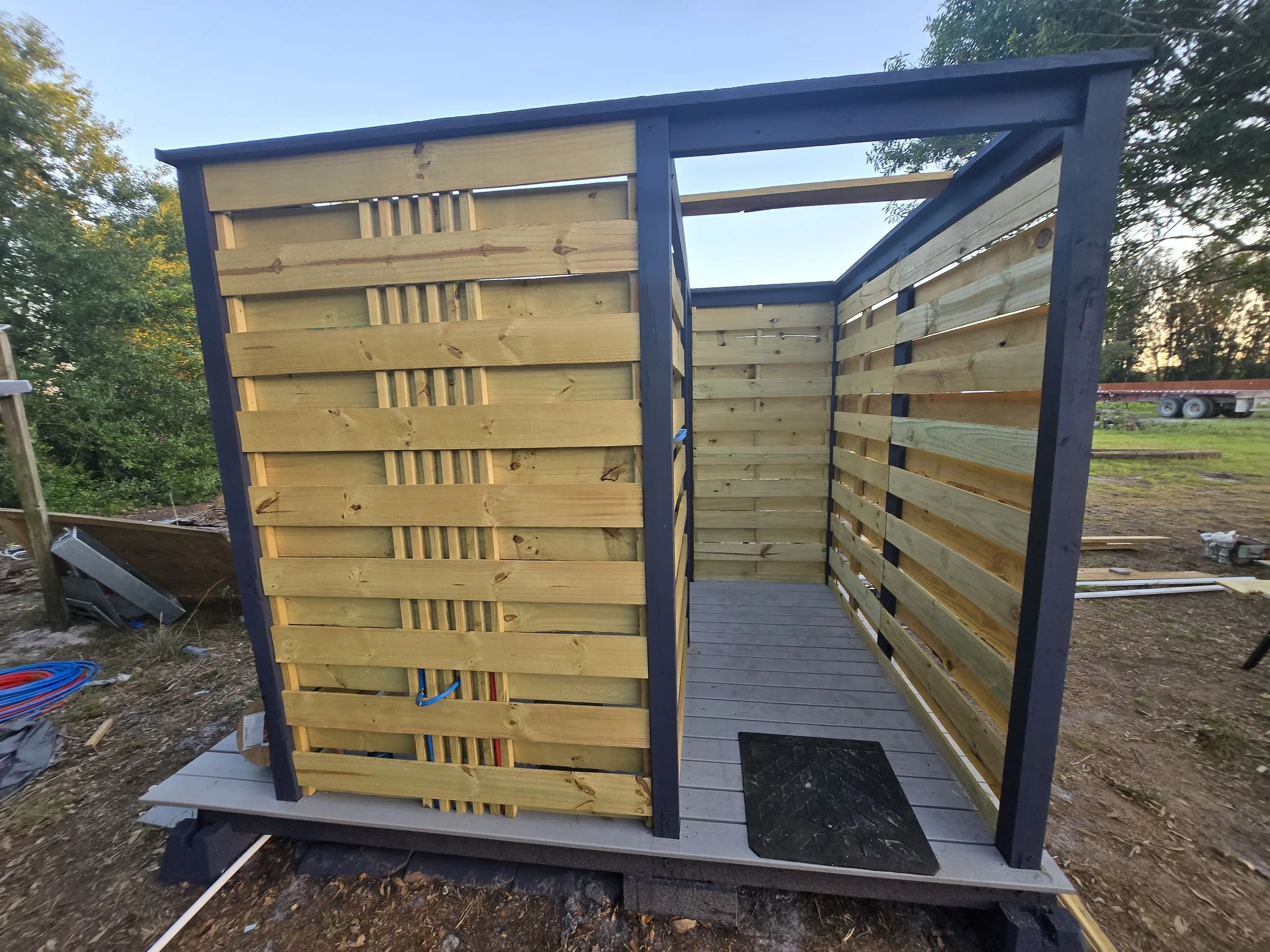 Built outdoor shower enclosure with wooden slatted walls and a wooden floor, fully off grid use.