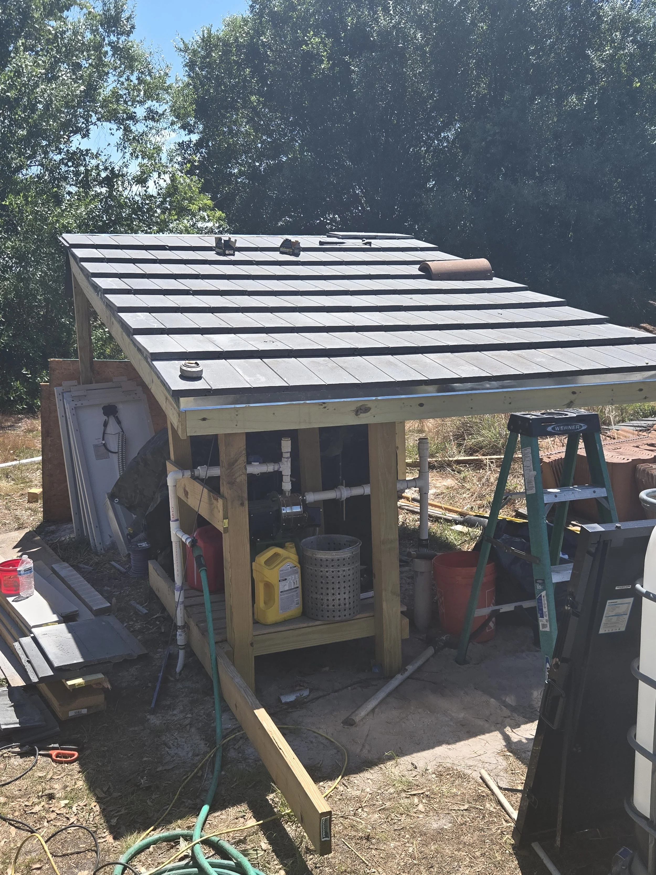Under construction shed with solar panels being installed on the roof