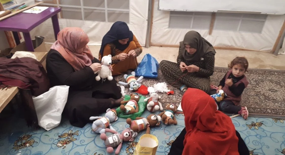 Syrian women knitting handmade toys as part of a skills and empowerment workshop in a refugee community