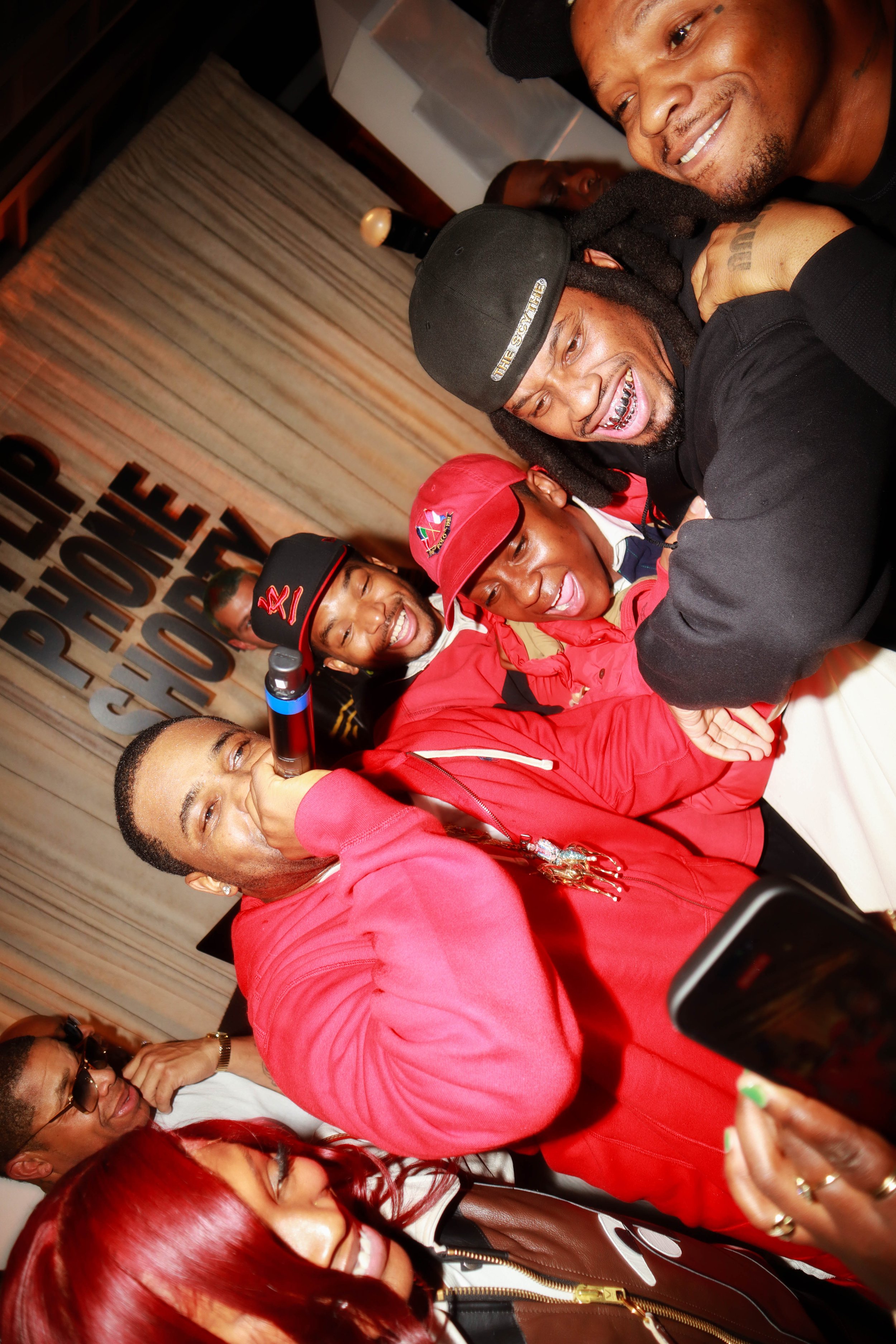 A group of people smiling and taking a photo together, with a sign in the background that says 'PEOPLE PHOTOGRAPHY'.