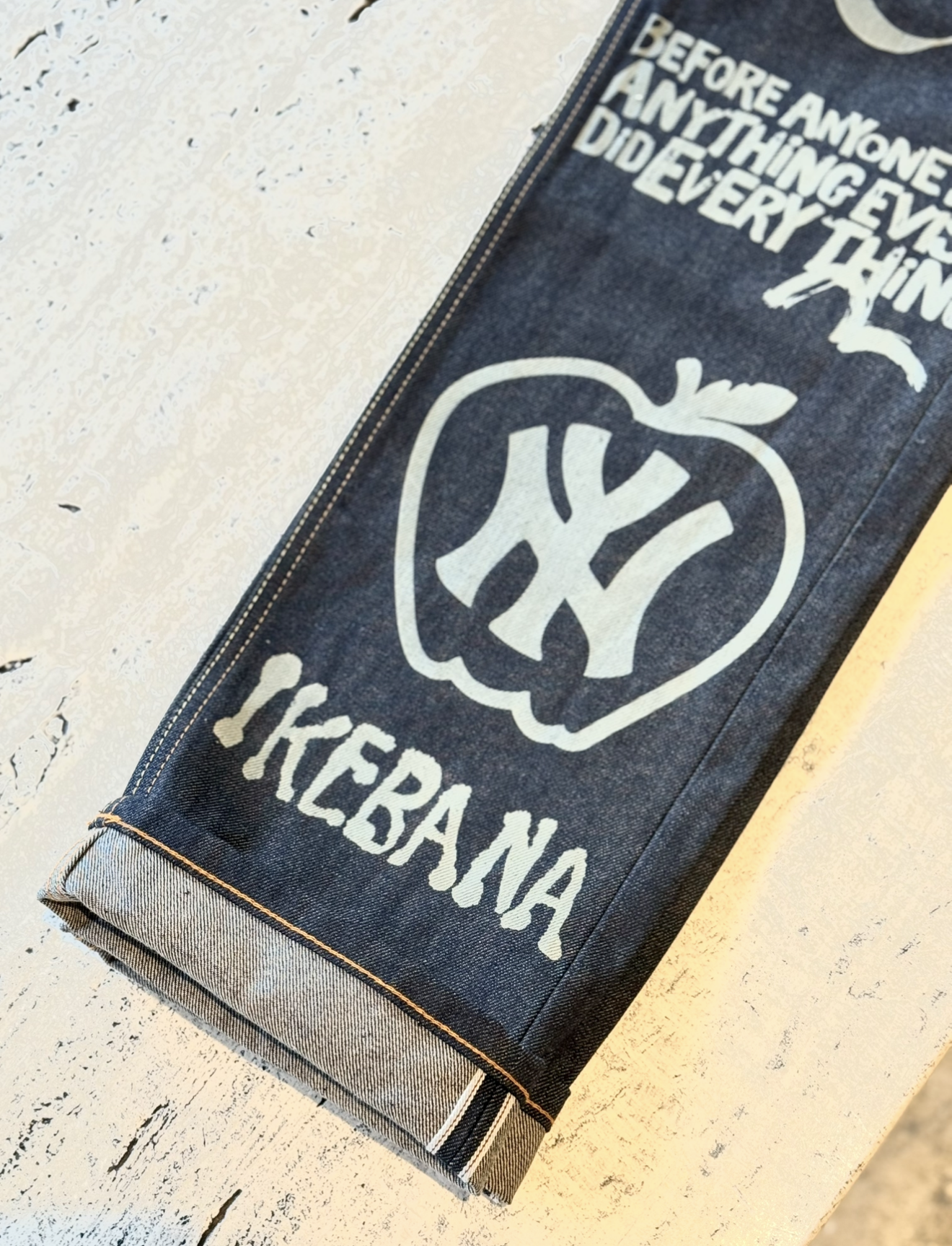 Denim fabric with white printed text and a graphic design, including a message about curiosity and a heart-shaped apple with the word 'YES' inside.