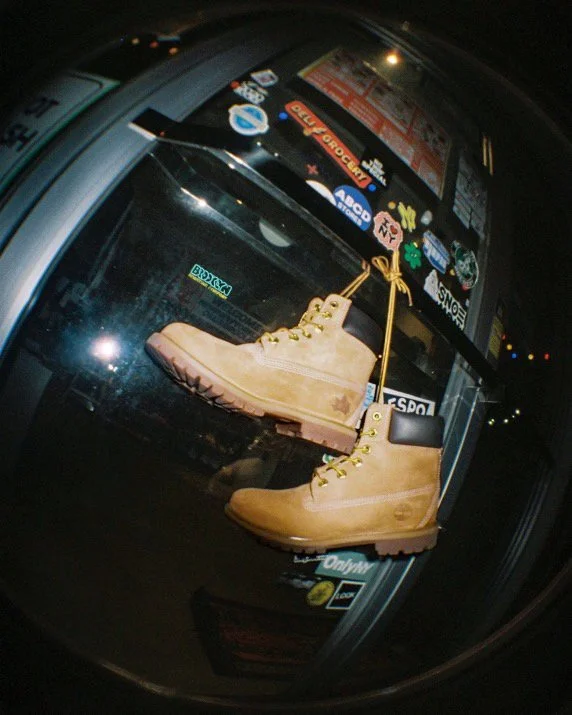 A pair of tan work boots displayed inside a car window with stickers.