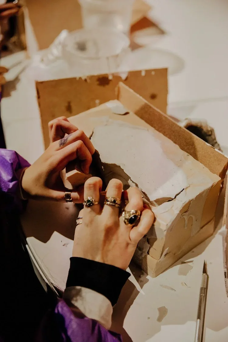 Shaping a clay piece by hand with tools