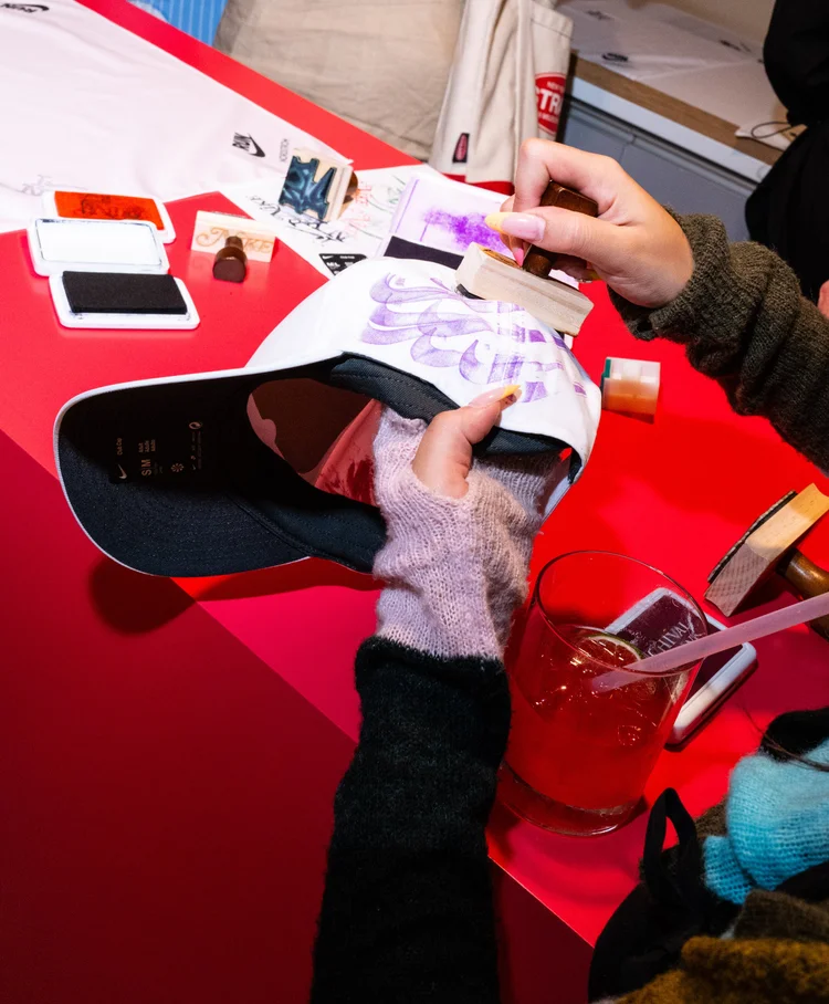 Guest stamping a white baseball cap with custom stamps at the live workshop table