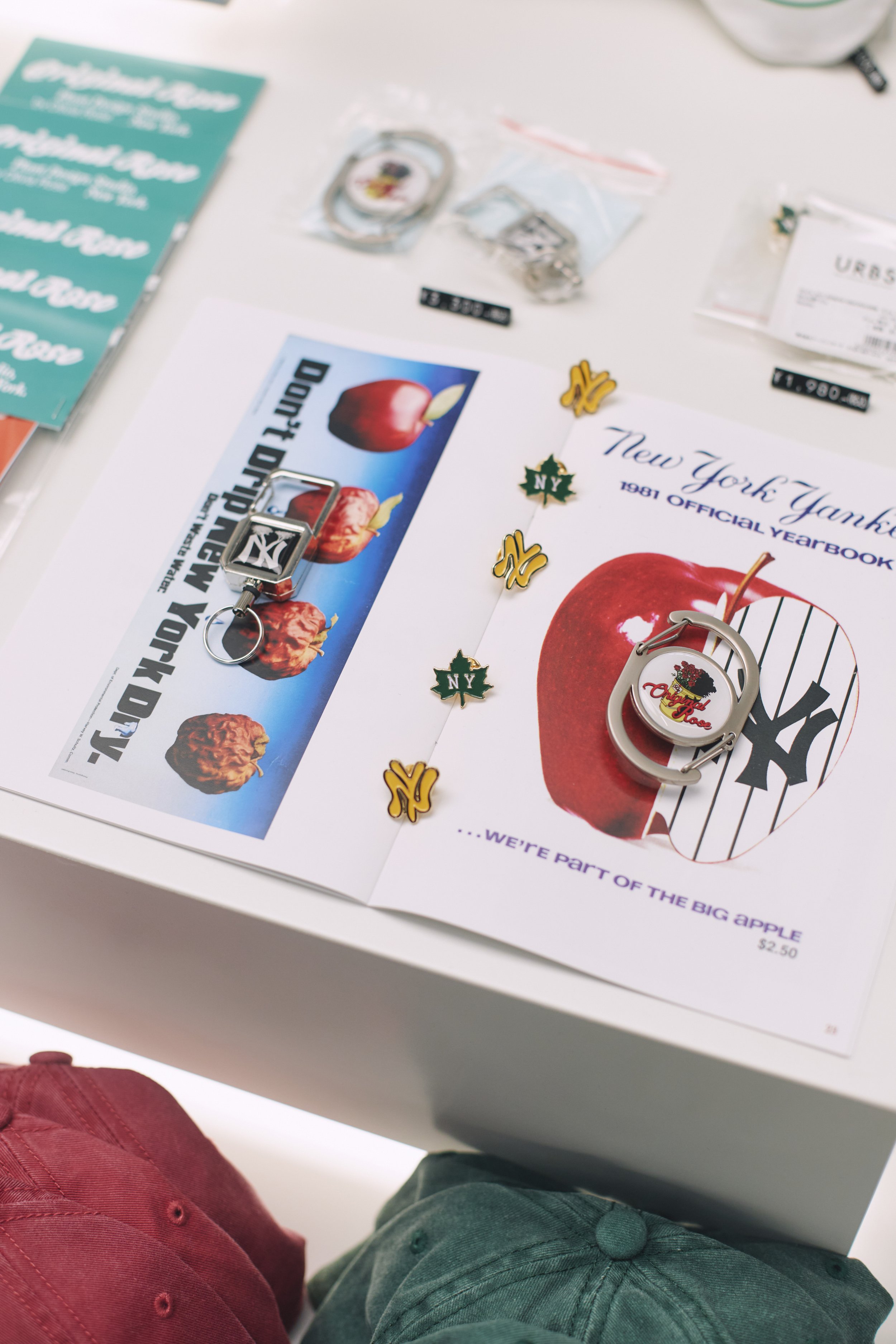Display of New York Yankees merchandise including keychains, pins, and a yearbook with a large apple image, set on a white table.