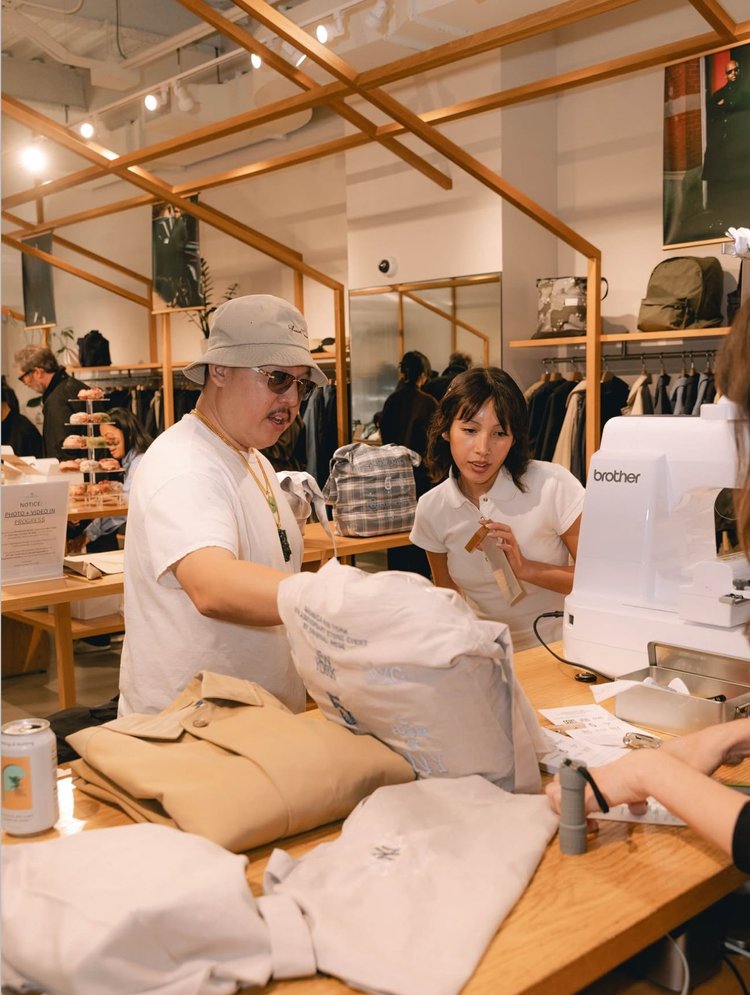 Guests picking up embroidered tote bags at the Nanamica anniversary event counter