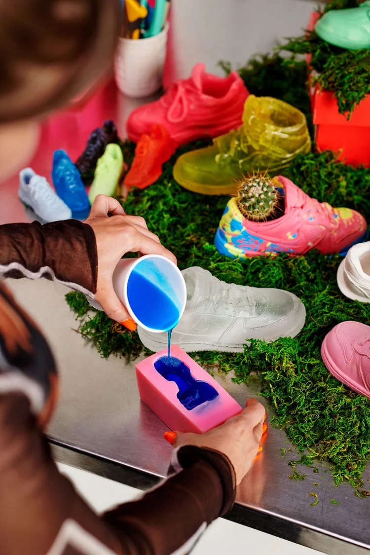 Pouring blue dye over pink soap among custom shoes and moss