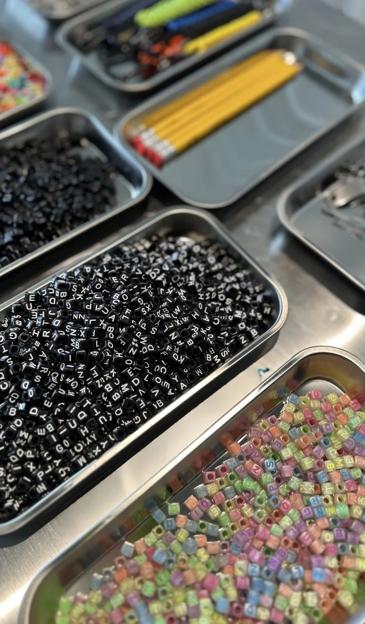Containers of colorful alphabet beads for personalizing sneakers and charms