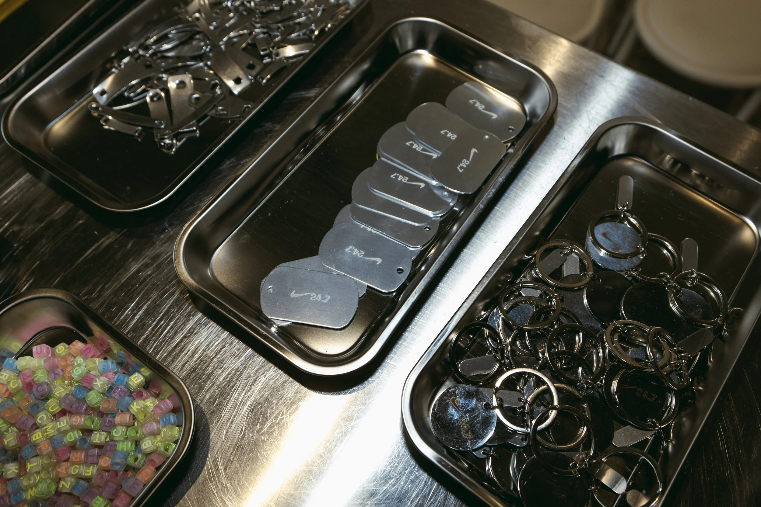 Metal keychains and colorful letter beads in stainless steel trays.