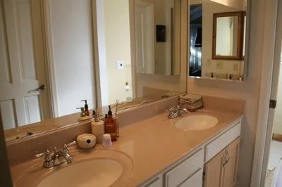 Bathroom vanity with two sinks, mirror, and toiletries.