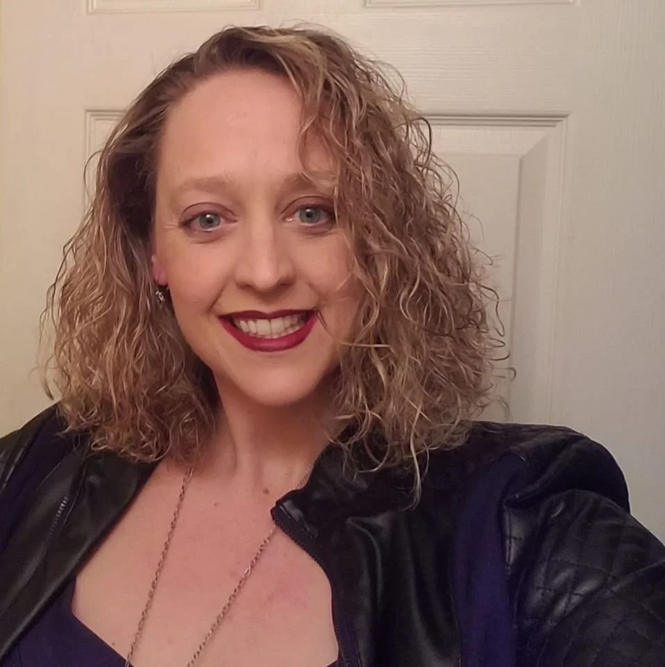 Woman smiling with red lipstick and blonde curly hair