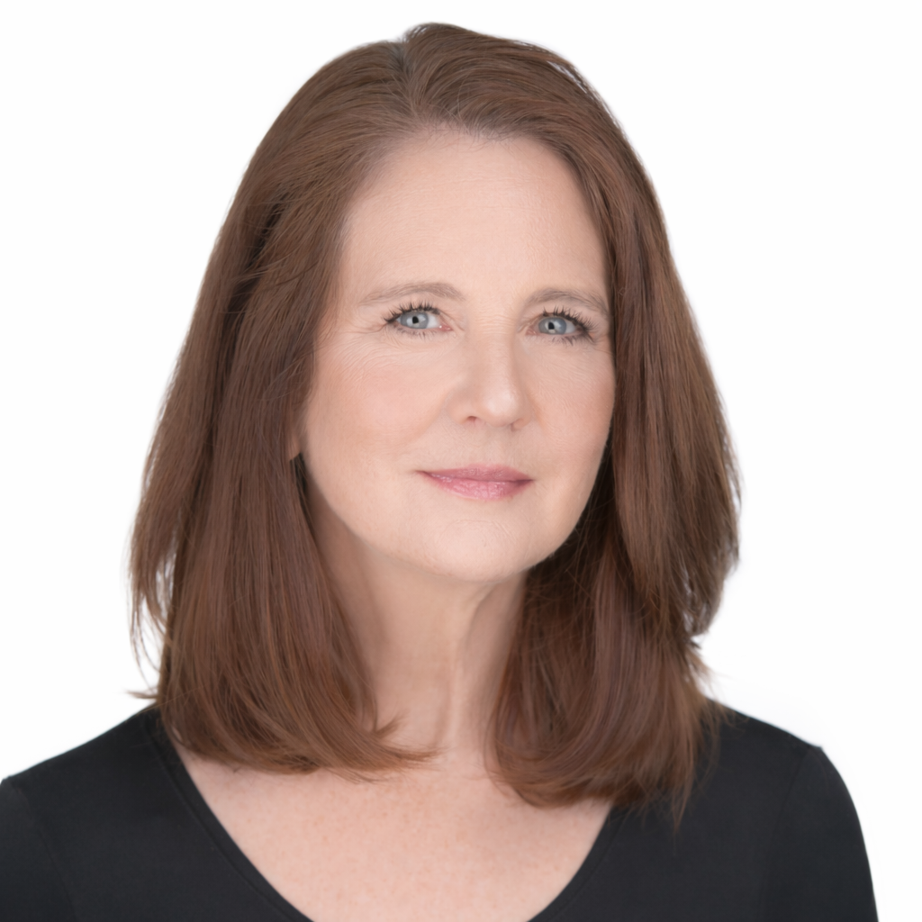 Tracy Foltz, executive and leadership coach who likes to help women at career crossroads, a woman with shoulder-length reddish-brown hair and blue eyes, smiling softly against a plain white background.
