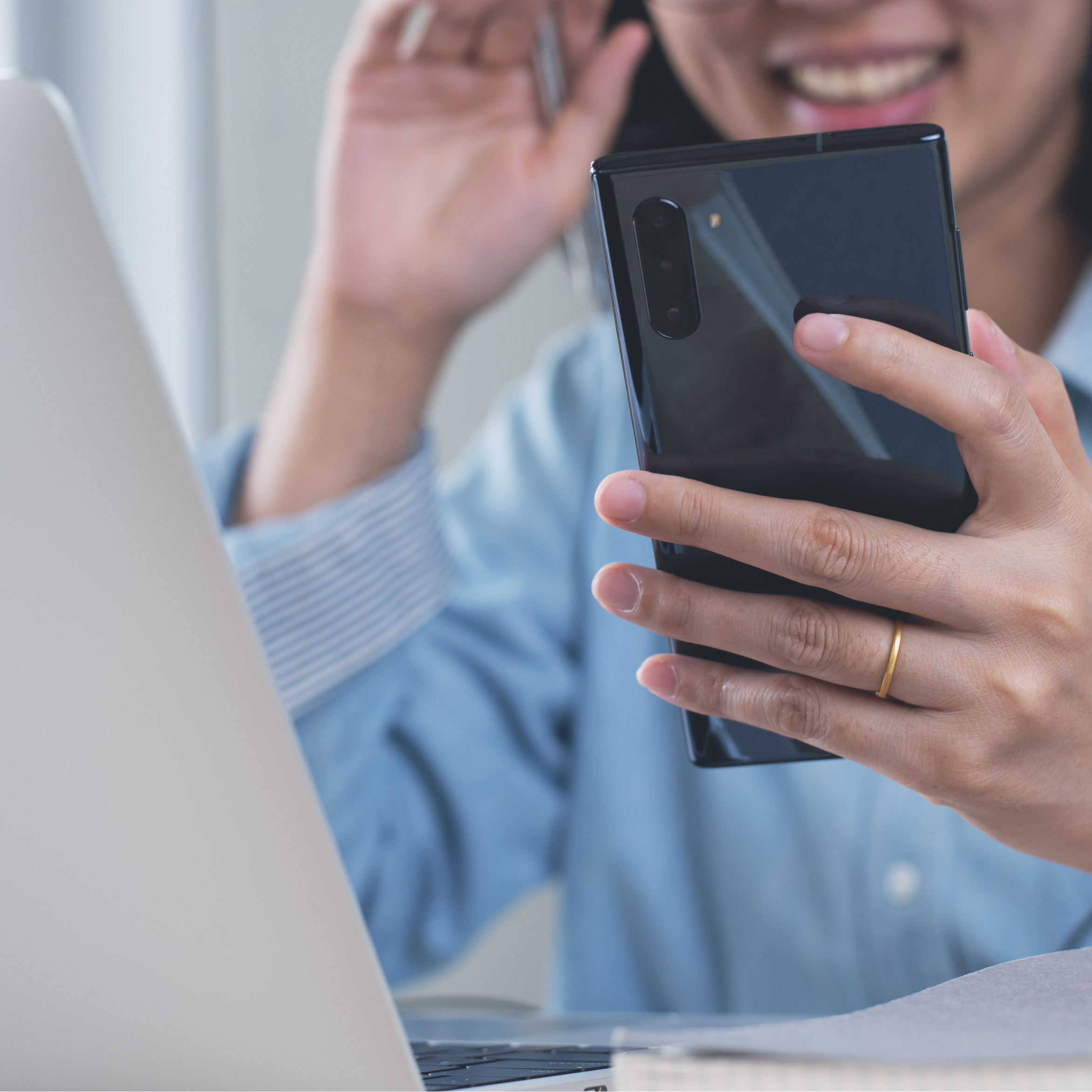 Person wearing a blue shirt smiles while holding a smartphone on facetime with Amanda Lucy to see homes on the market.