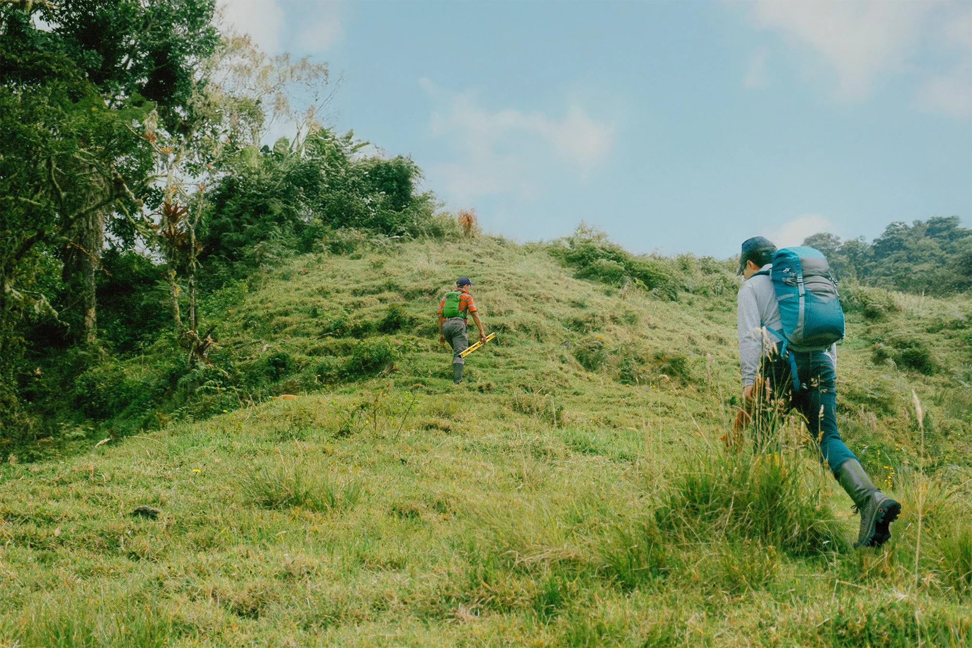An image of two land stewards hiking up a hill.