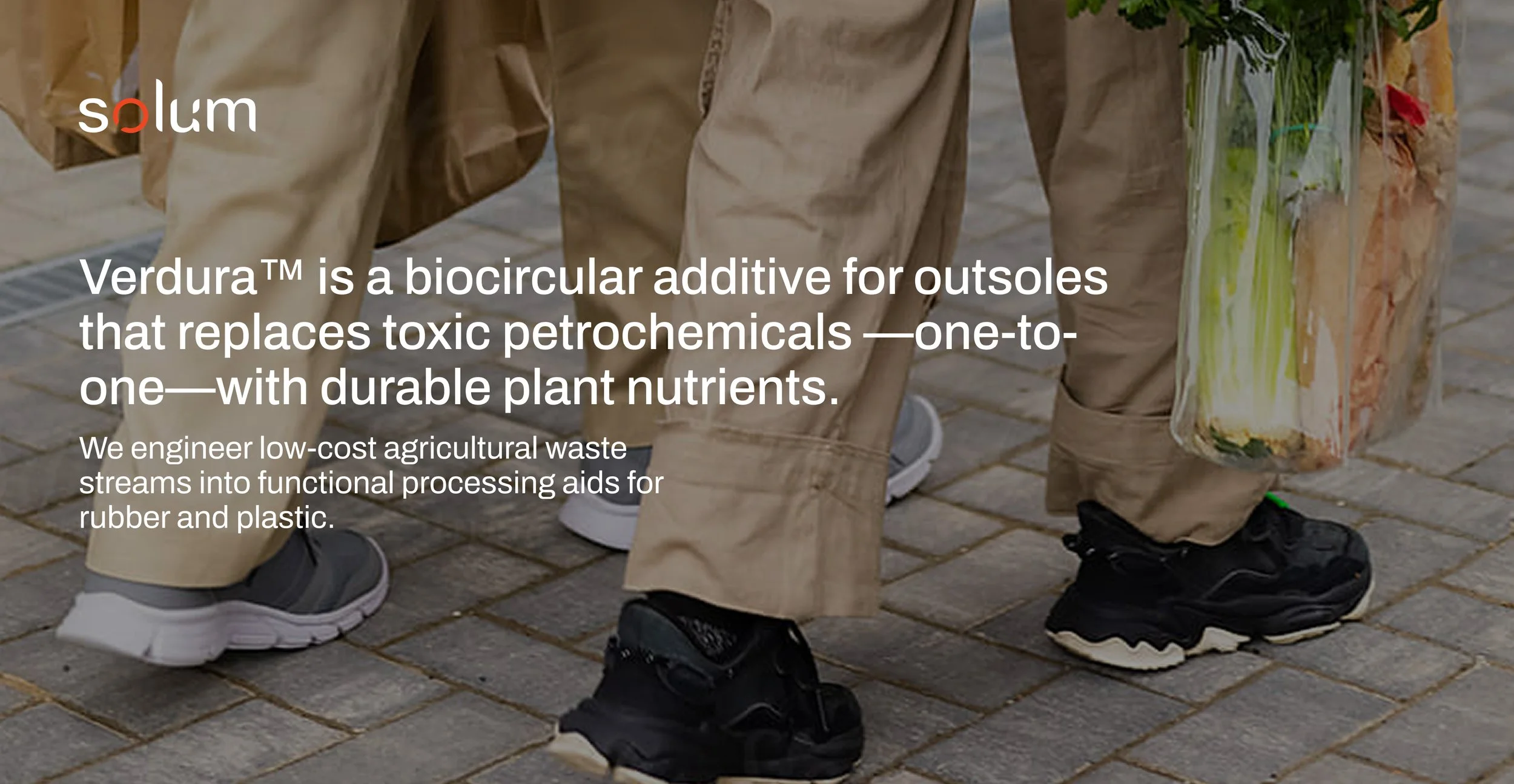 Close-up of people wearing sneakers walking on a brick pavement, carrying bags and a glass container with plants and papers.