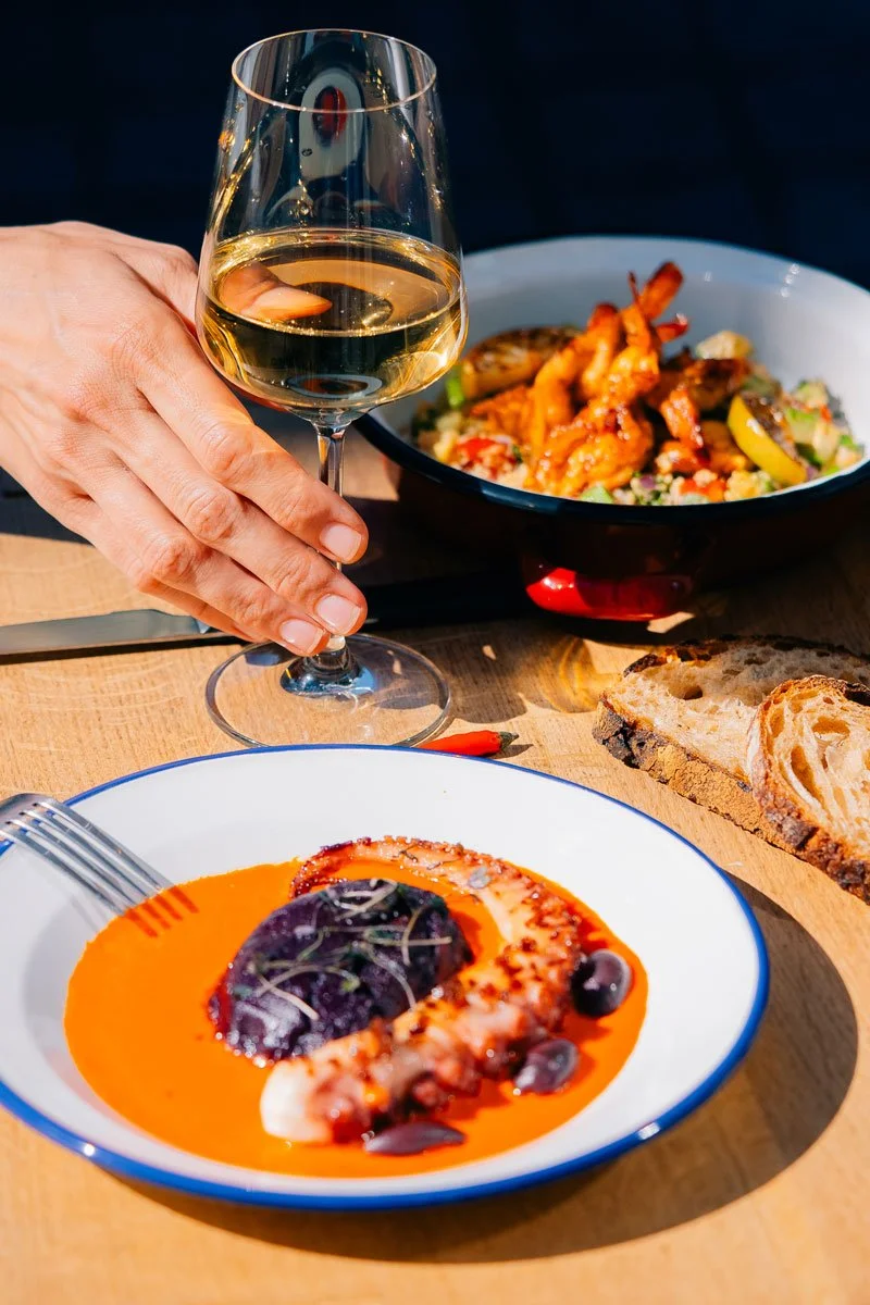 person hold win glass at table with modern food