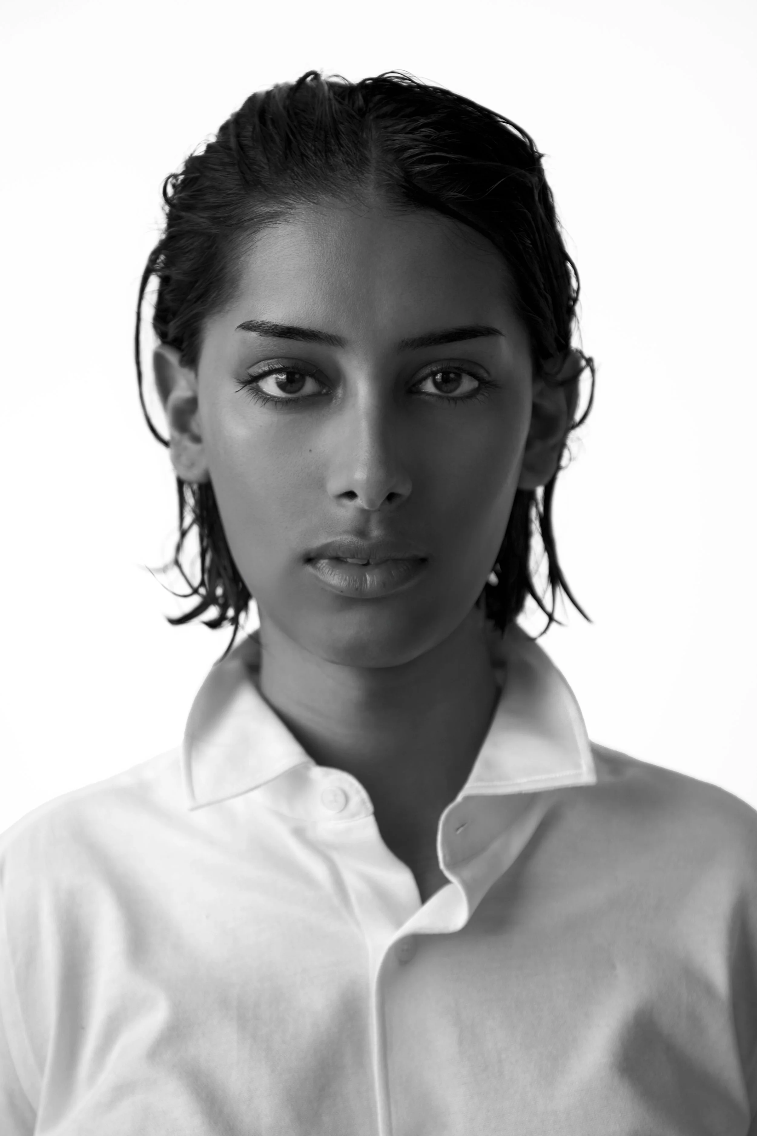 Black and white portrait of a woman with wet hair, wearing a collared shirt, looking directly at the camera.
