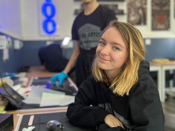 Tattoo school student smiling during hands-on tattoo training class