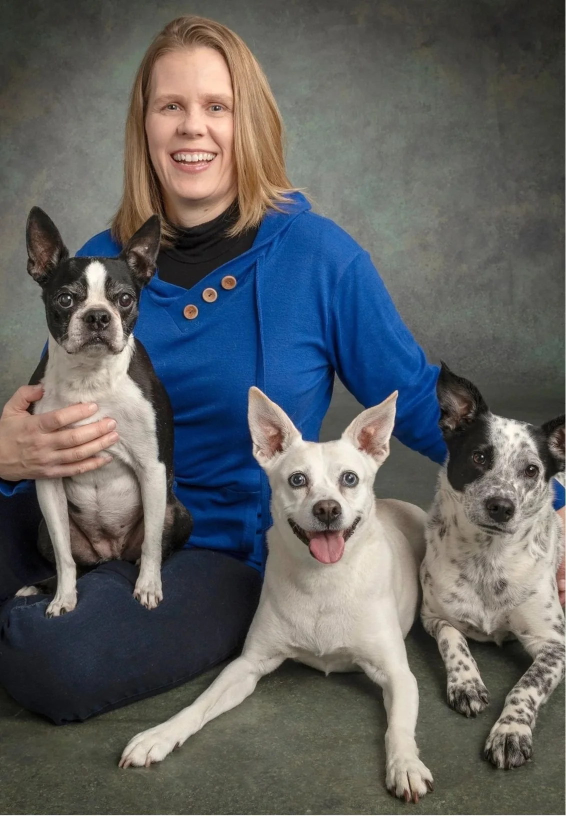 Ellie Feldmann, therapist specializing in human-animal bond, sits with three dogs.