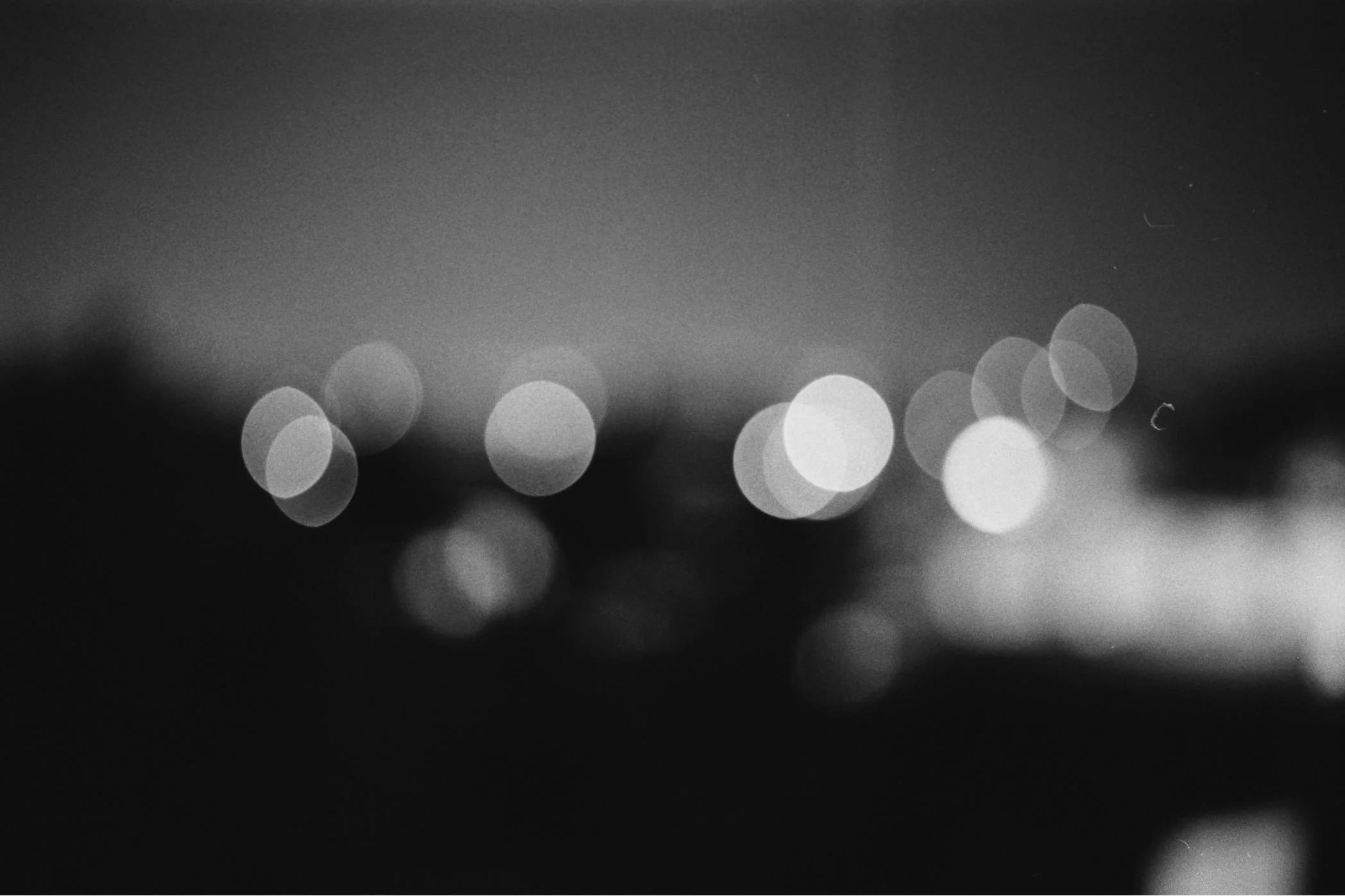 A blurred black and white photo of city lights at night, creating bokeh effects with circular light shapes