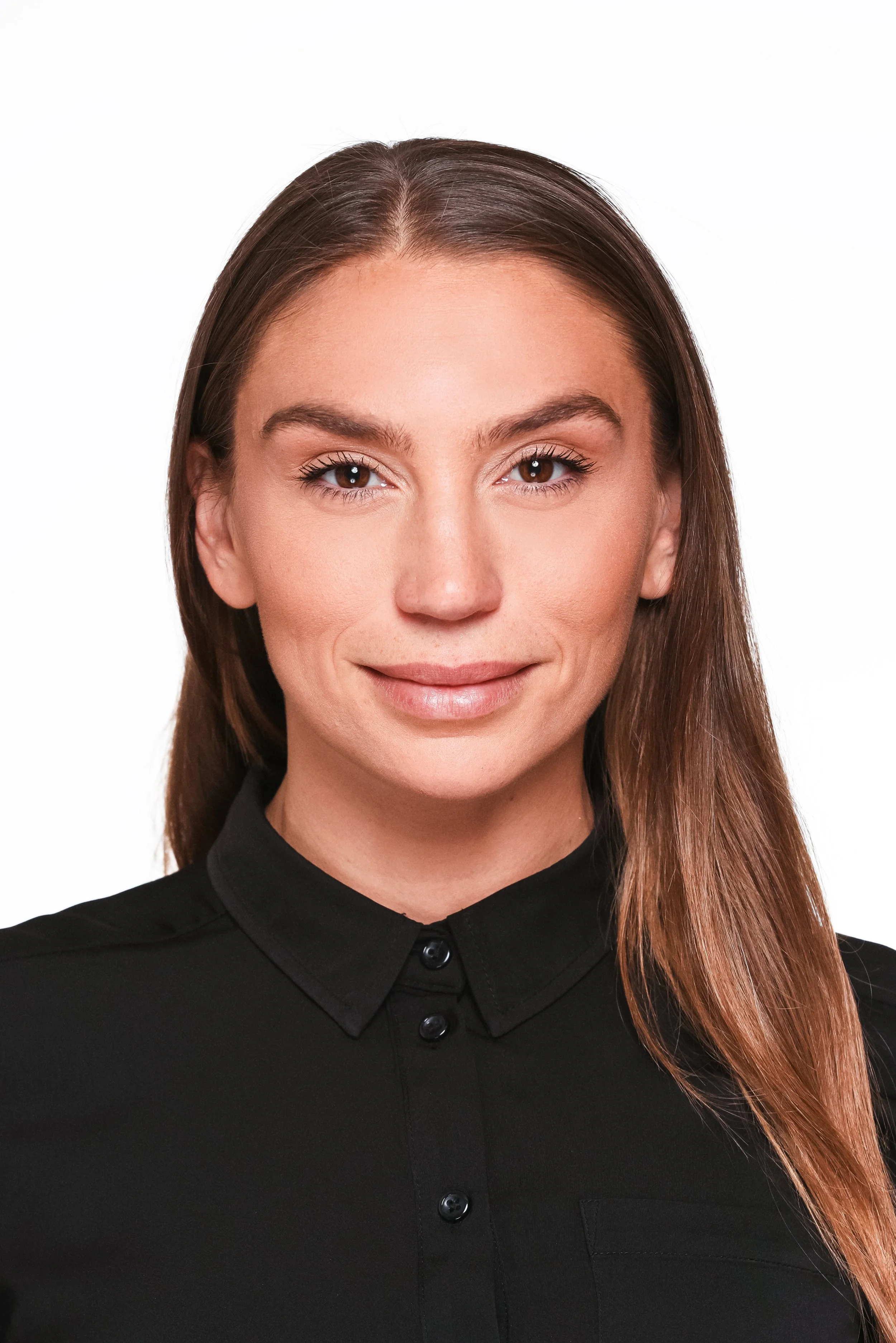 Headshot of a woman with brown hair and light makeup, wearing a black button-up shirt, smiling slightly against a white background.