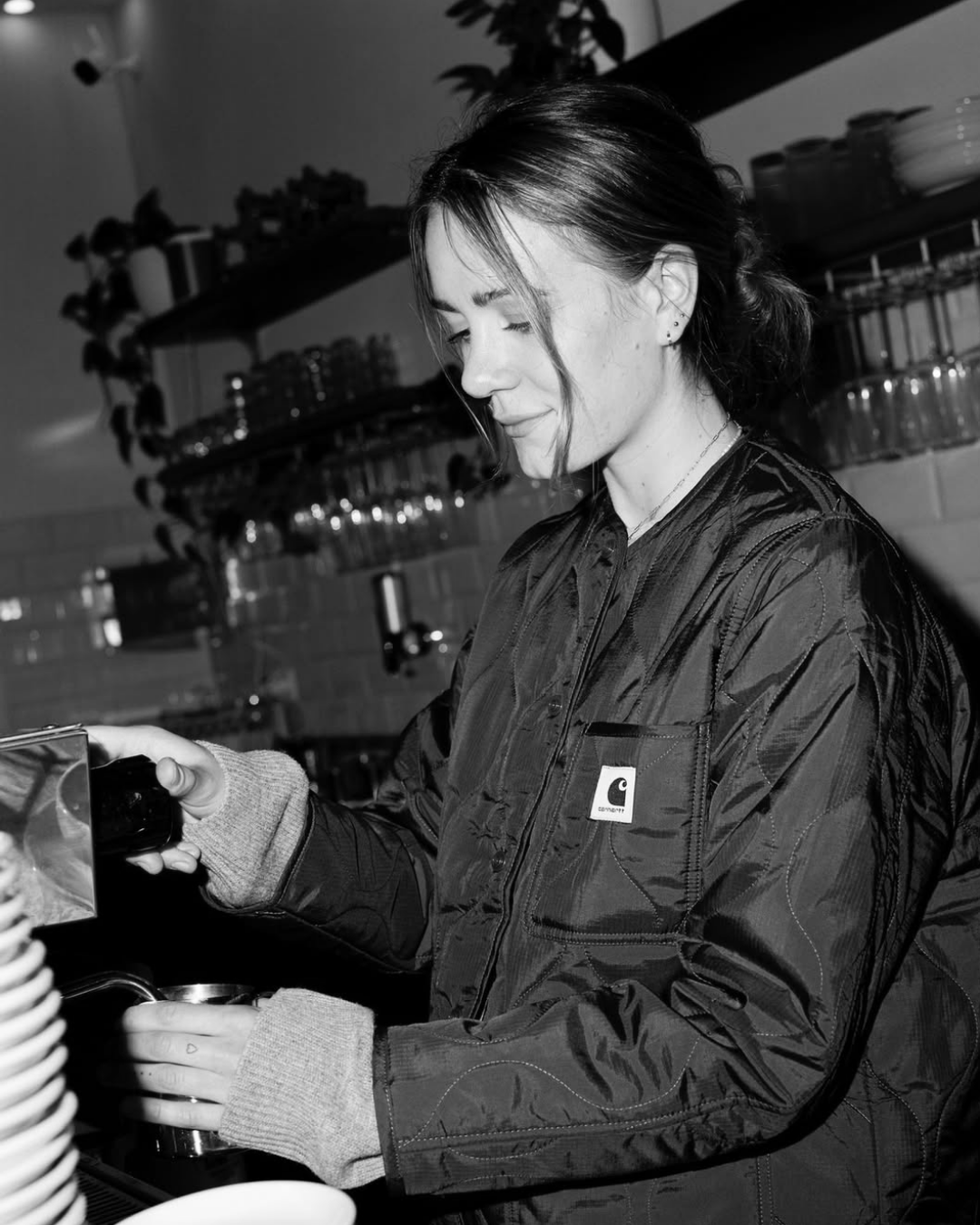 Frau bei der Zubereitung eines Getränks in einer Café-Umgebung, schwarz-weiß