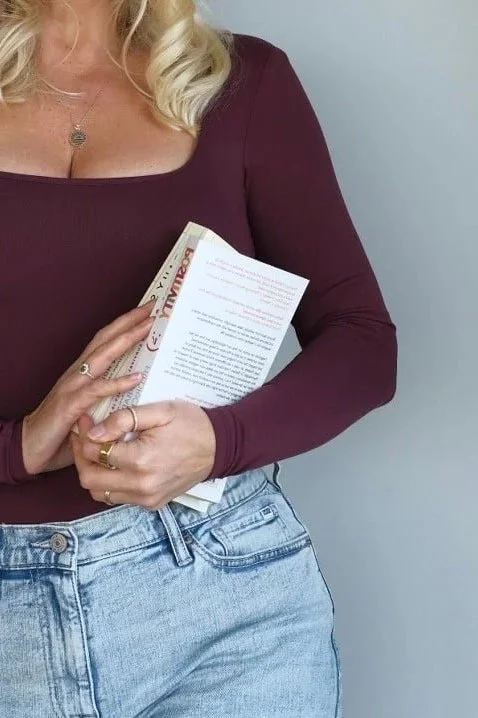Woman holding a booklet or guide, representing learning, clarity and personal growth within somatic coaching and nervous system work