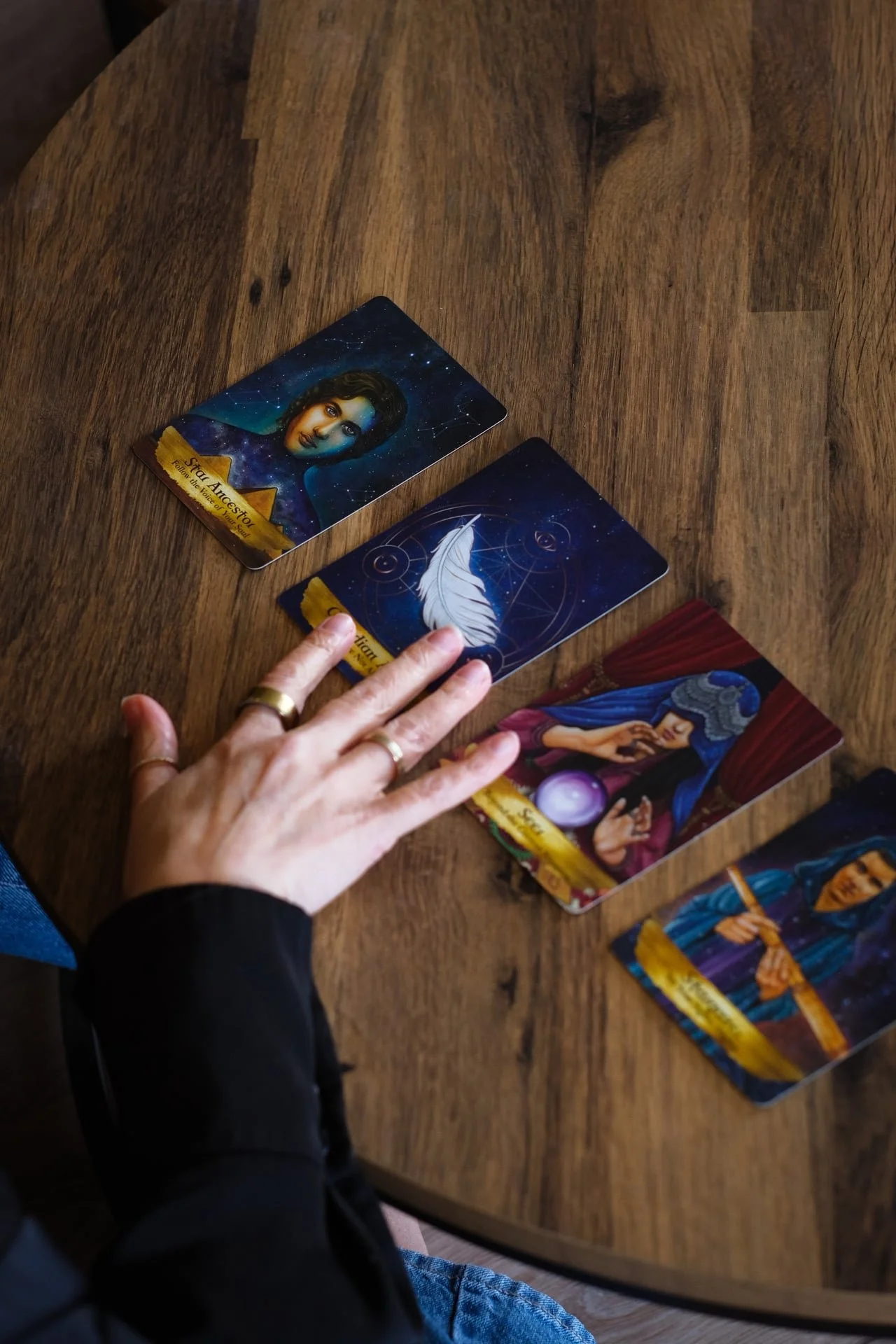 Hands reaching toward tarot cards on a wooden table, representing intuition, reflection and deeper self-awareness within personal growth work