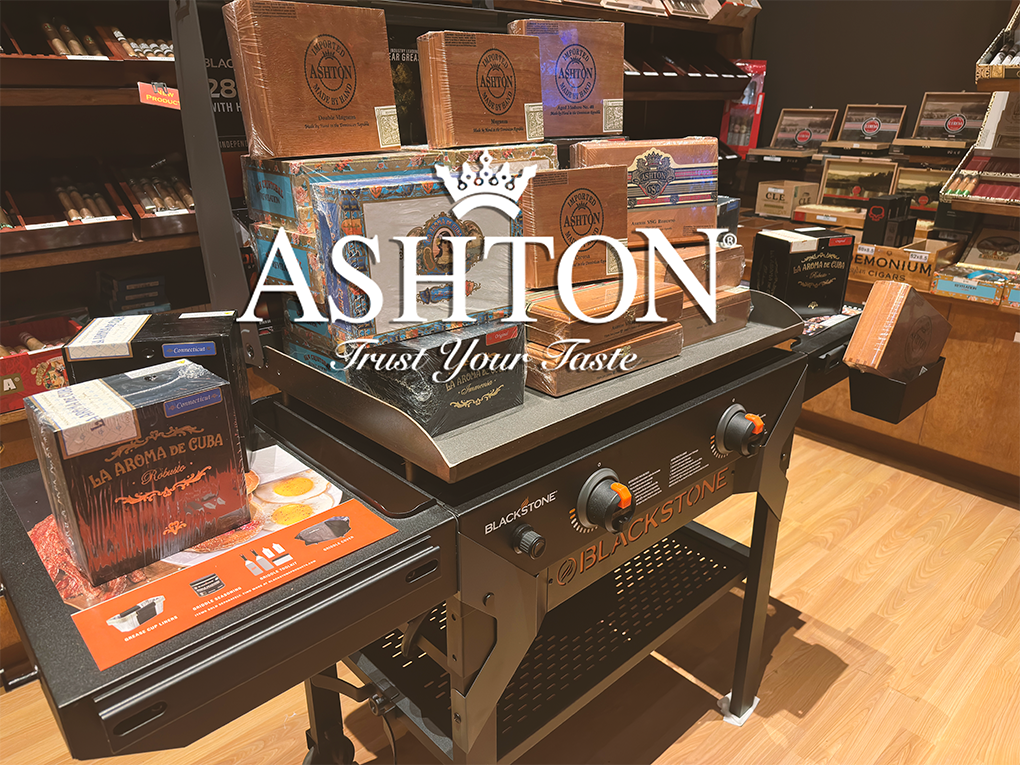 Display of Ashton cigars on a black Blackstone grill in a cigar shop.